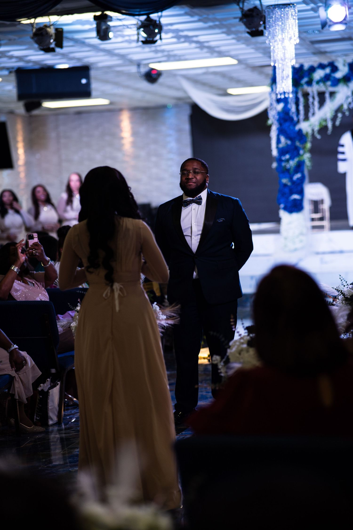Bridesmaid and groomsman walk towards each in blue and white floral wedding.