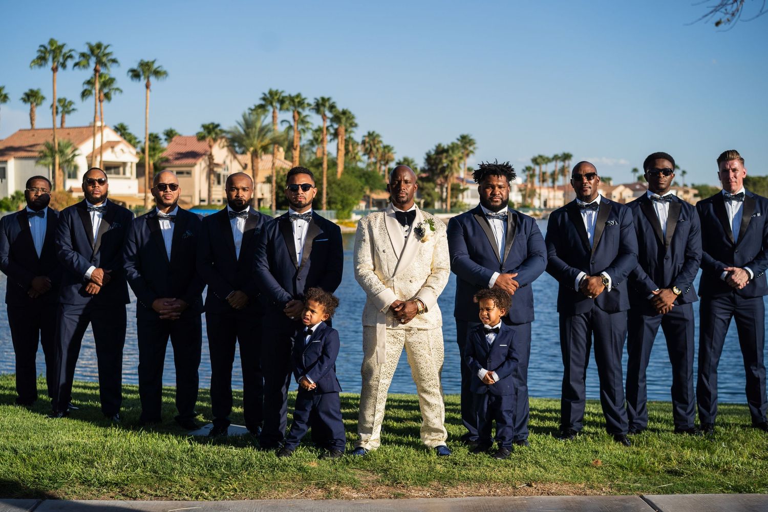 Groom, twin ring bearers, and Groomsmen posing in horizontal line with their matching suit jackets.