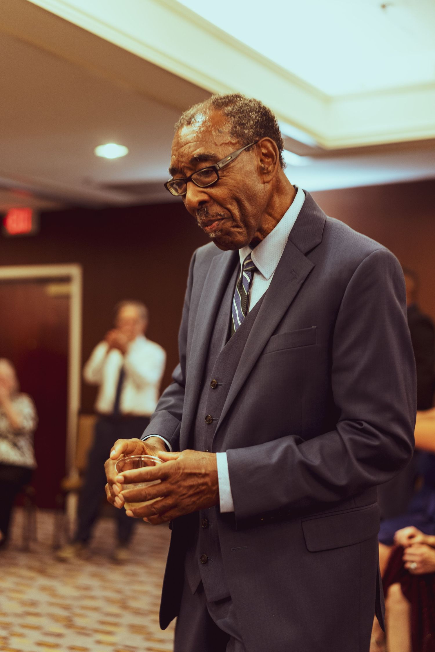 Old man in suit jacket folding his hands peacefully reflecting on life.