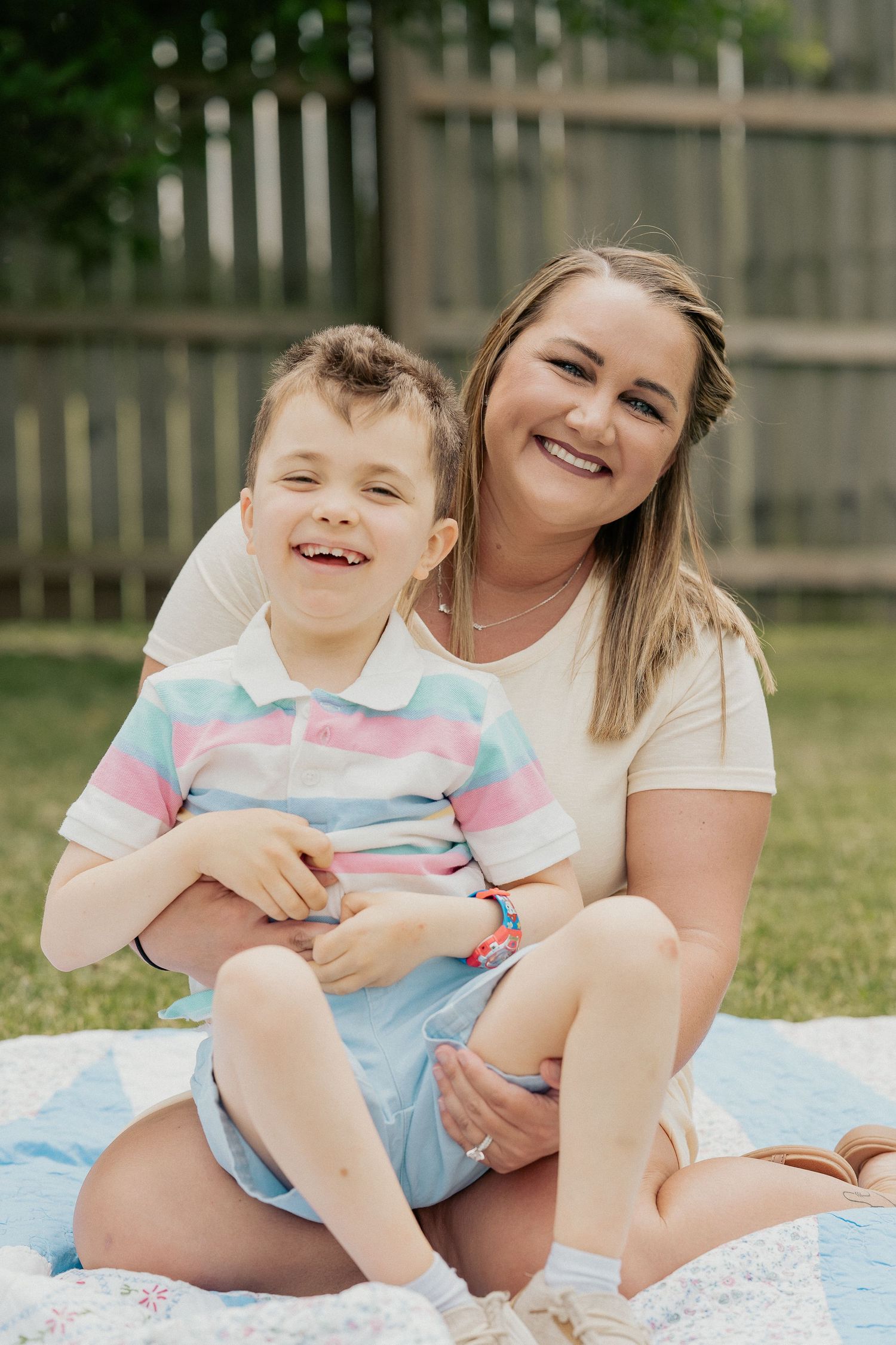 Mother and child share loving moments together while sitting on a blanket in their backyard.