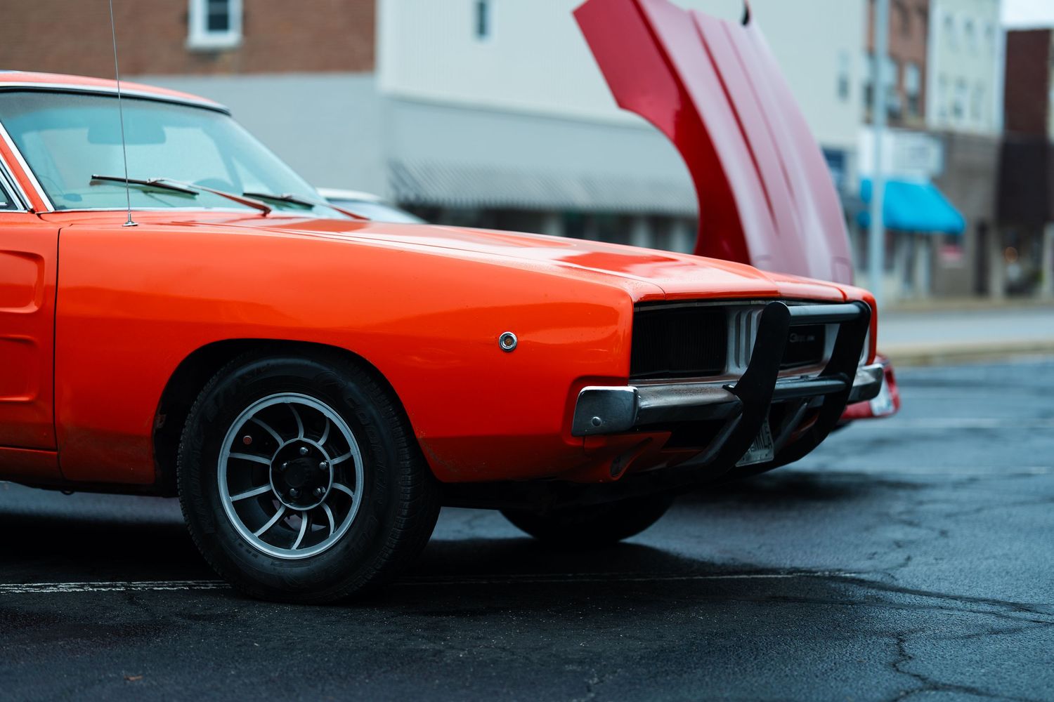 Close-up details of a red vintage sports car showing chrome wheels and body panels.