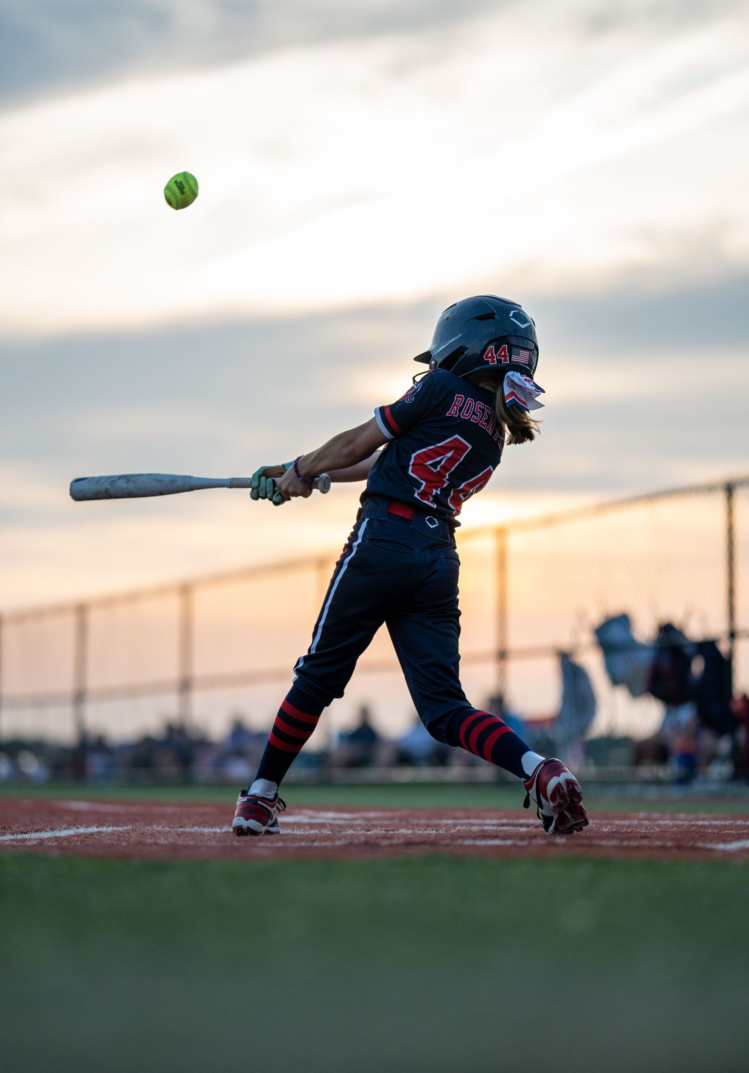 Sequence of baseball player silhouettes hitting a ball at sunset on a baseball field.