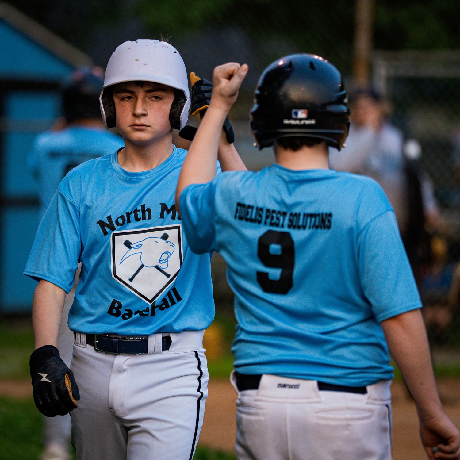 14U baseball players in light blue jerseys during a game.