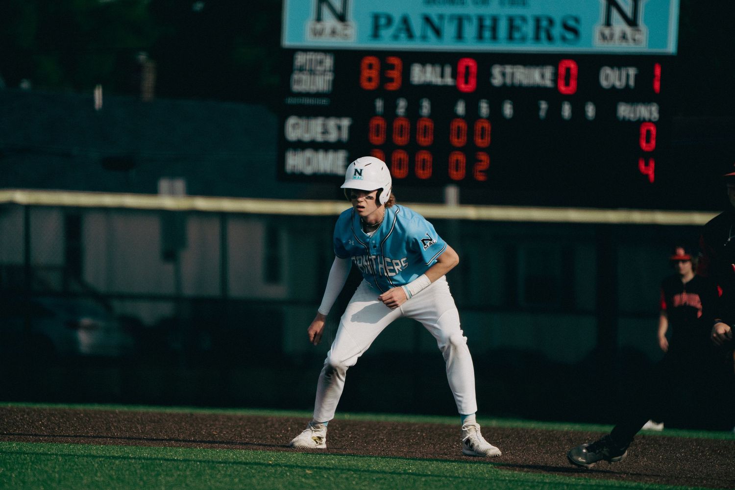 Baseball game scoreboard showing Panthers team name and scores under stadium lights.