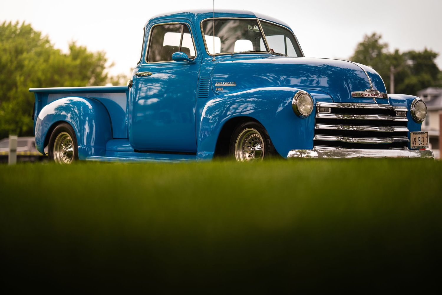 Row of classic blue vintage pickup trucks lined up for display at a car show.