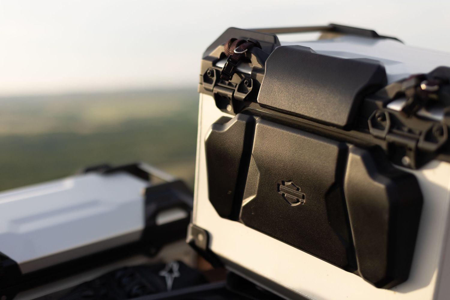 Close-up of a DJI drone camera gimbal mount against a scenic green landscape background.