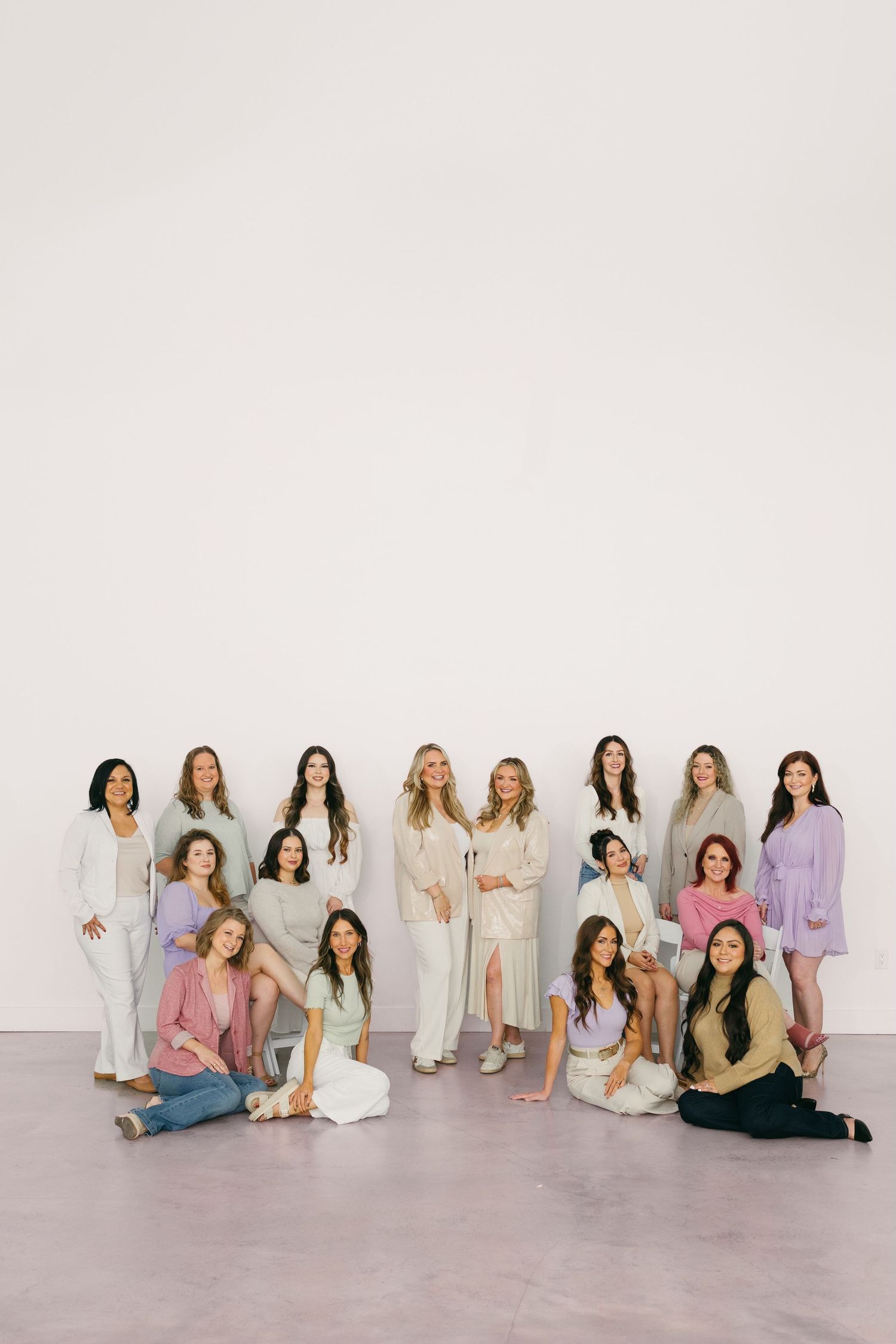 Women in coordinated neutral outfits pose together for a group portrait against a white backdrop.
