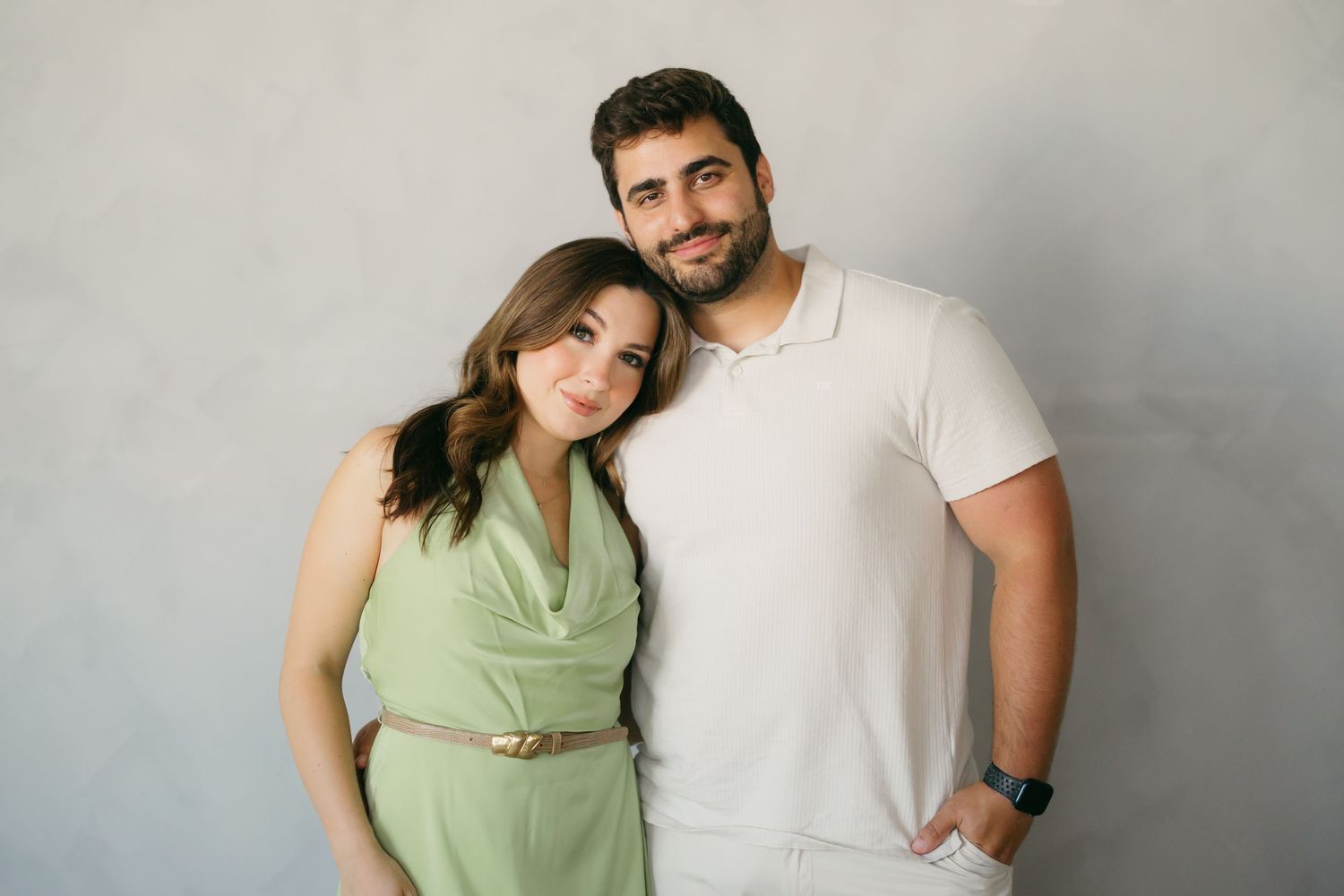 A couple in casual attire poses together against a gray background in a series of connected portrait shots.