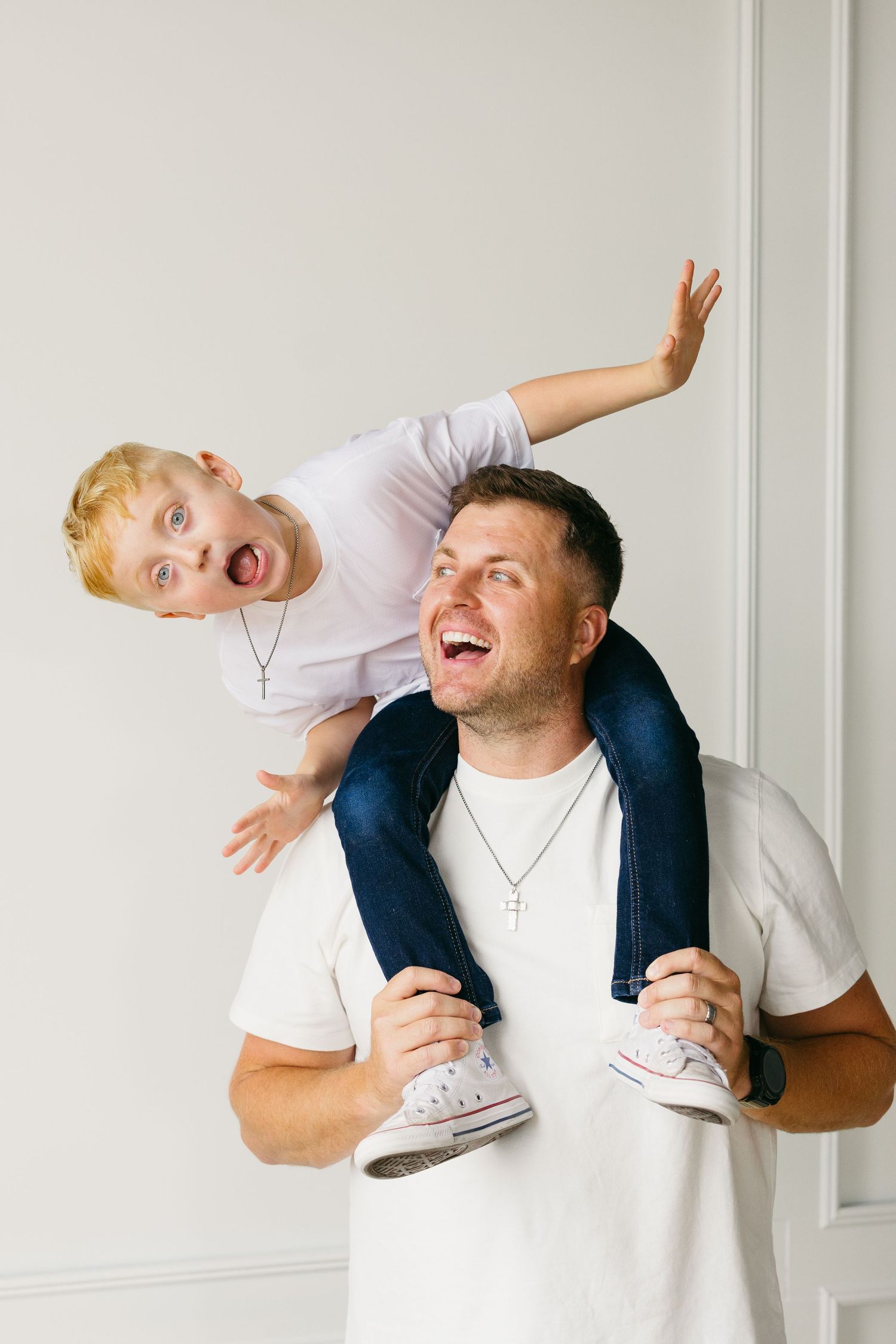Playful moment between parent and child with piggyback ride against white wall.