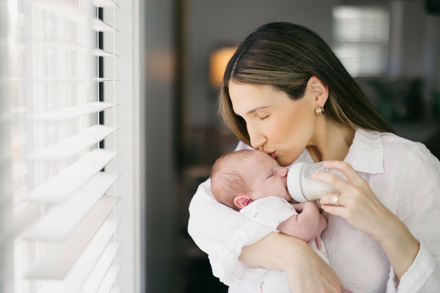 A tender moment between parent and newborn baby as they share loving kisses and cuddles in a bright room.