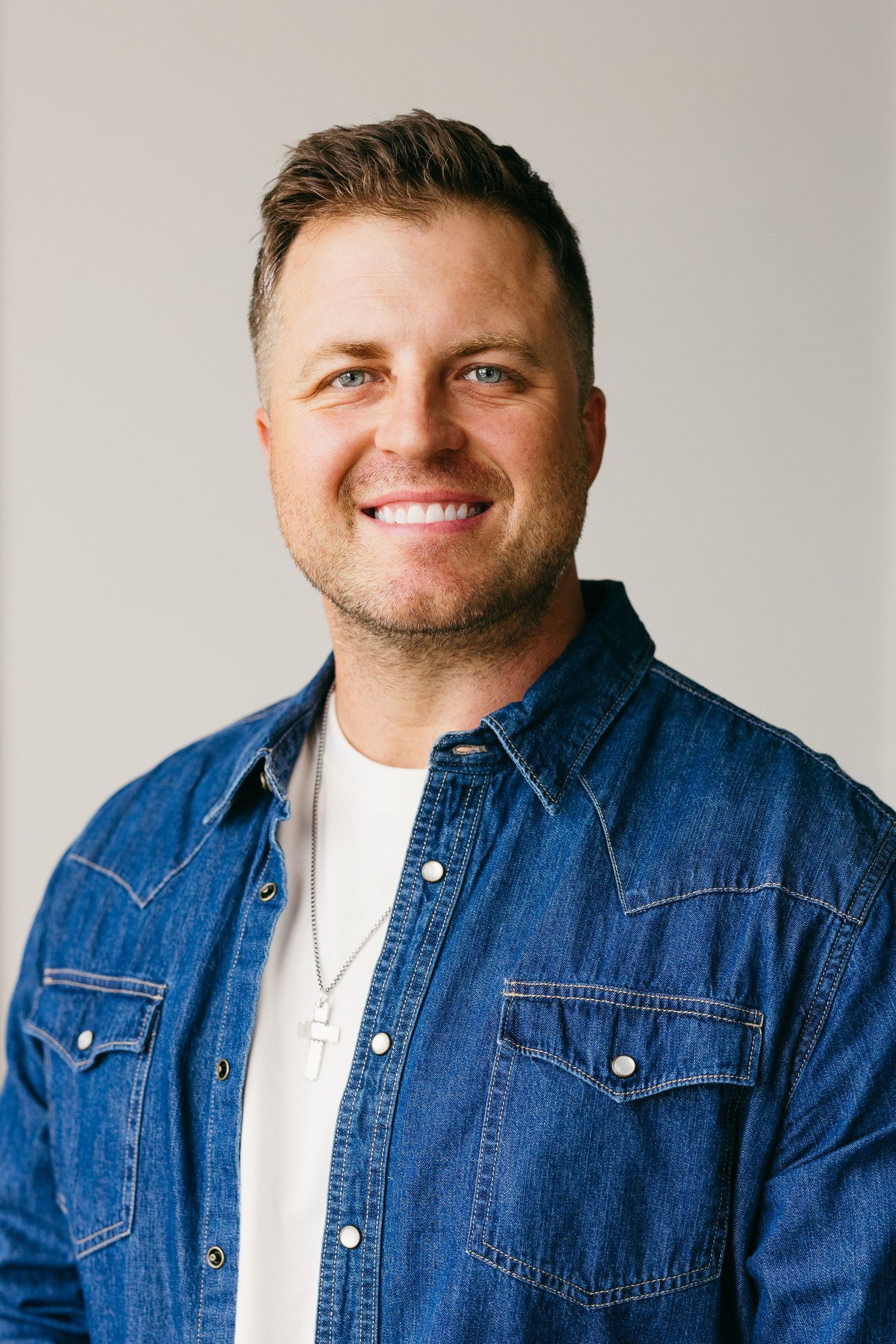 Casual headshots of person wearing denim jacket and white t-shirt against light gray background.