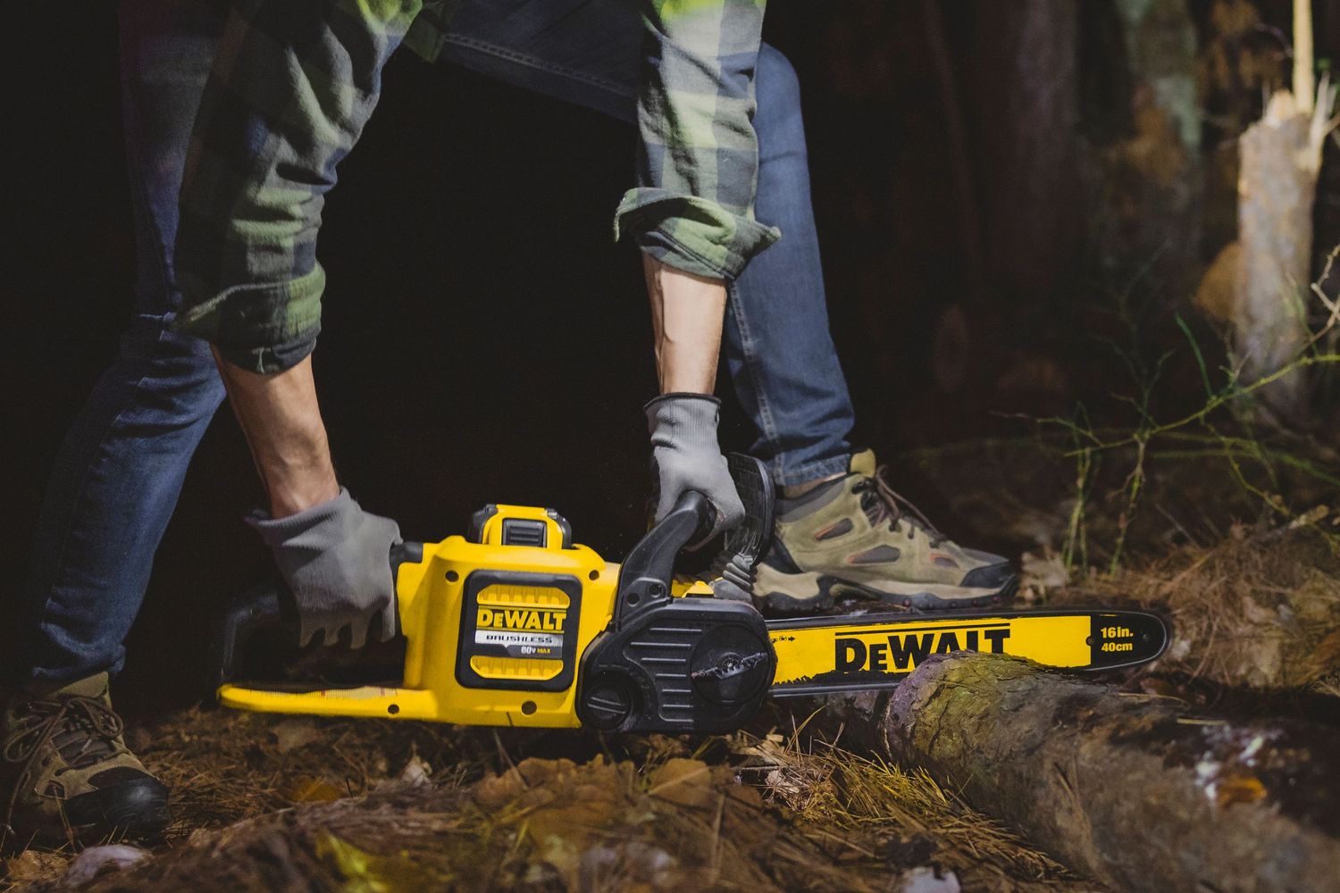 Yellow DeWalt power tools laid out on forest ground.