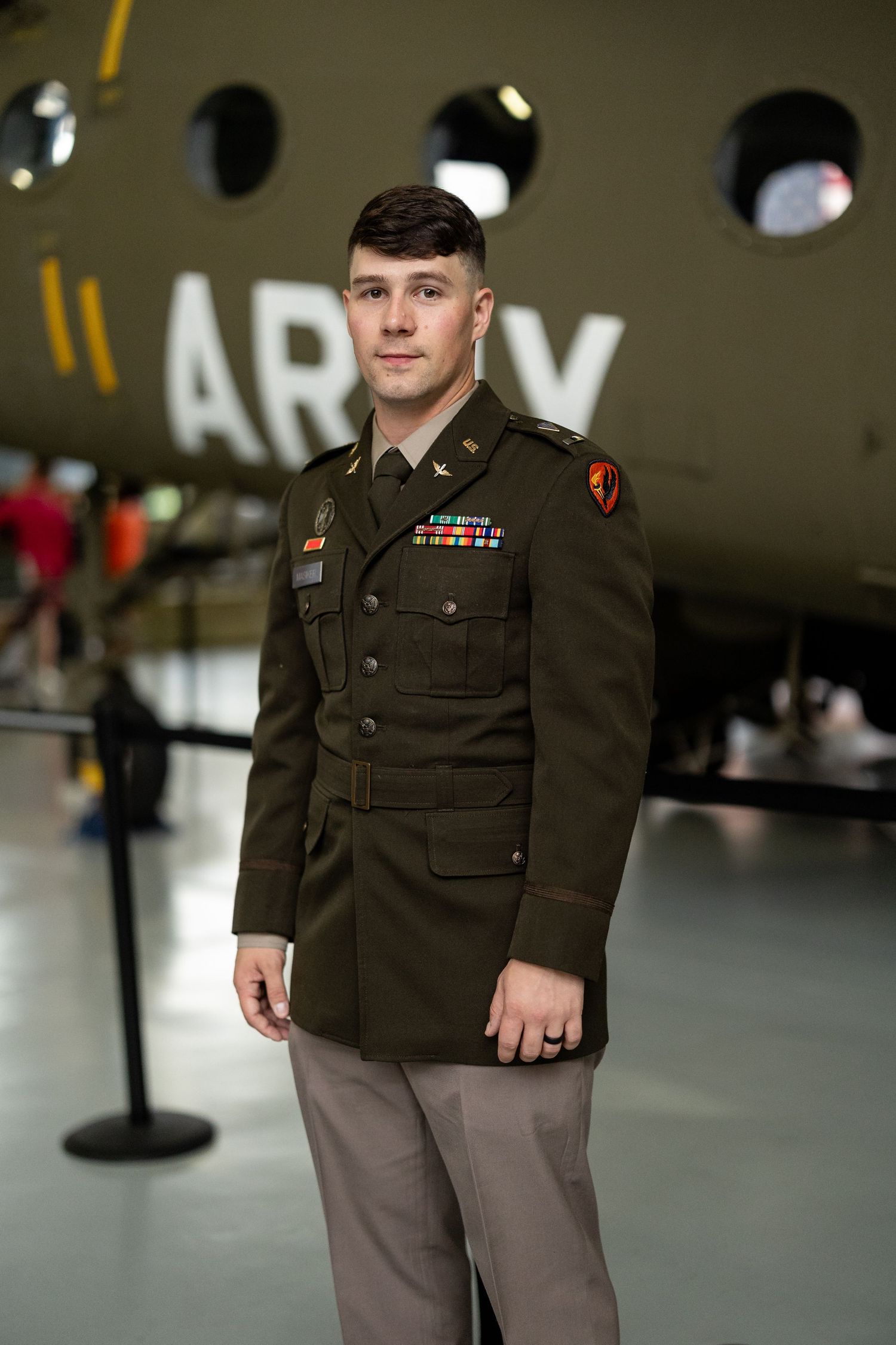 Military officer in dress uniform standing in a formal indoor venue.