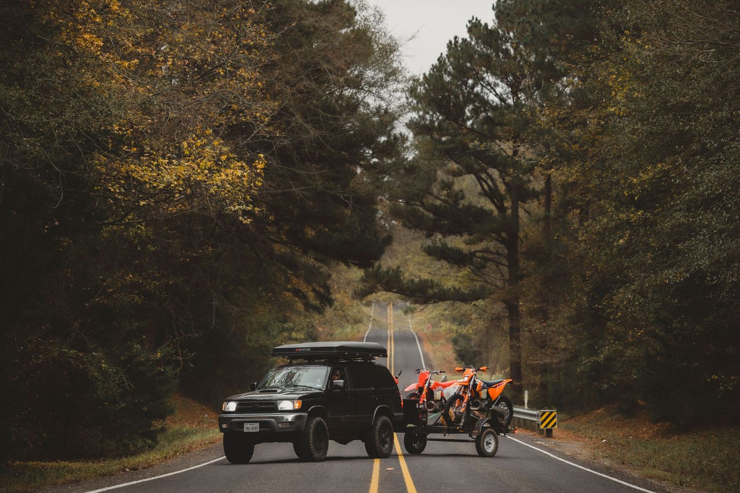Cars driving on a winding forest road during autumn season.