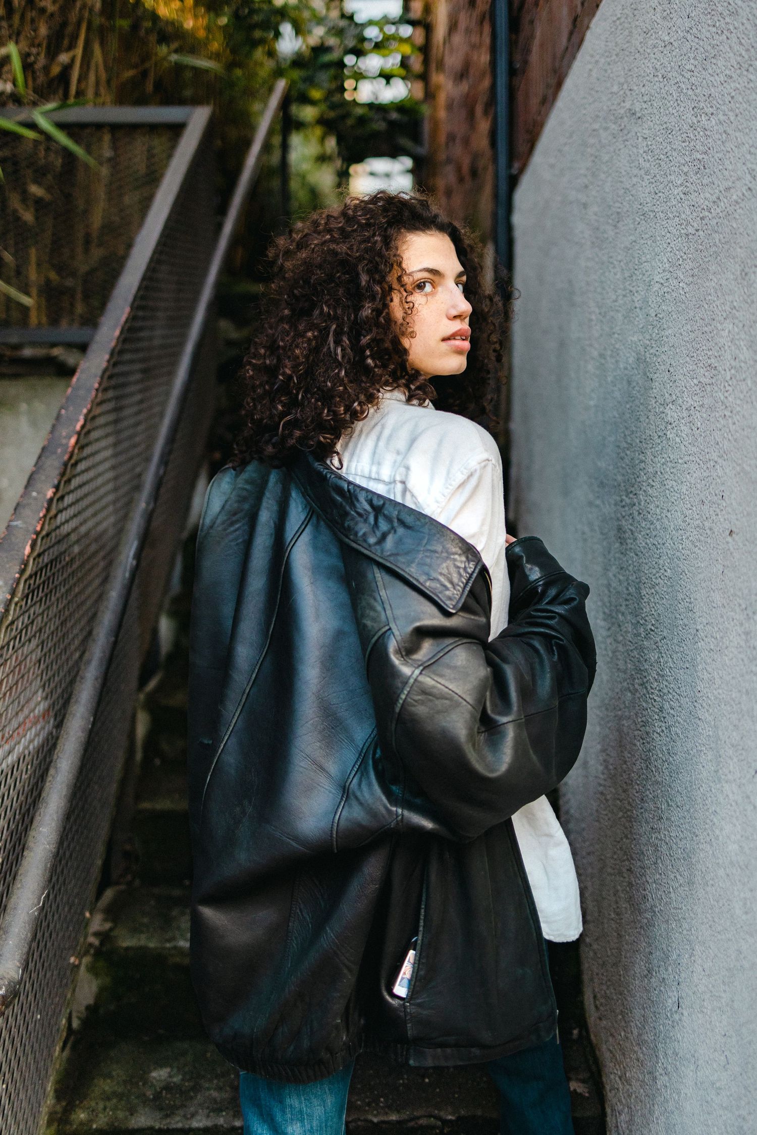 Editorial style fashion portraits showcasing a casual outfit against an industrial concrete wall.