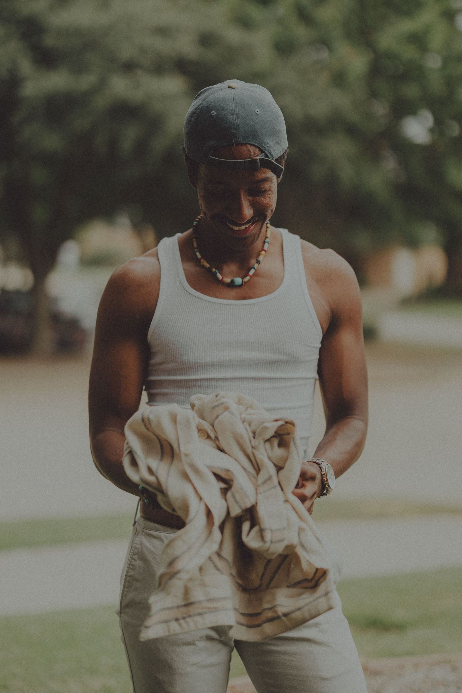 A series of four connected photos showing someone wearing a white tank top adjusting their khaki pants outdoors.