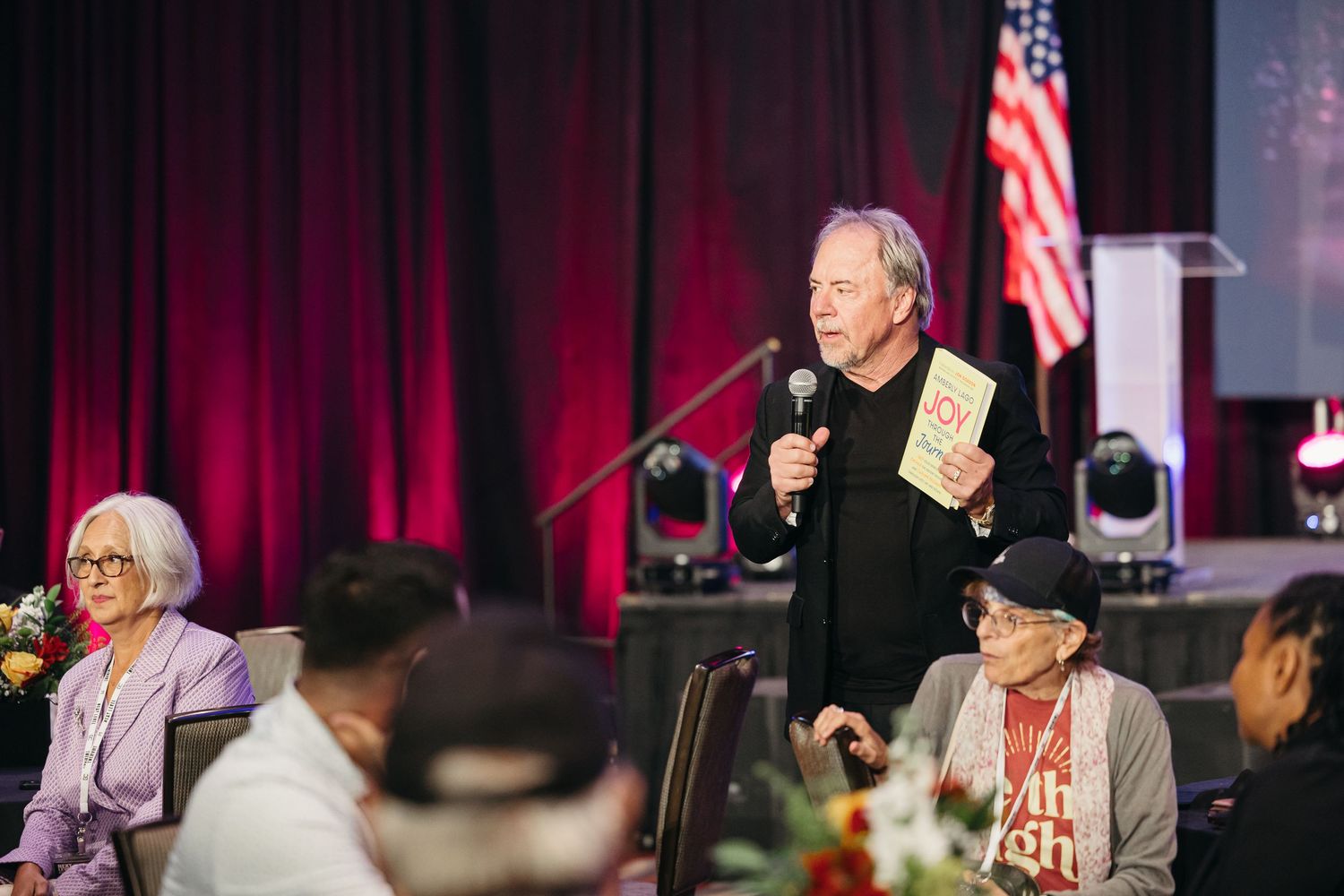 Professional conference stage setup with American flag and red curtain backdrop.