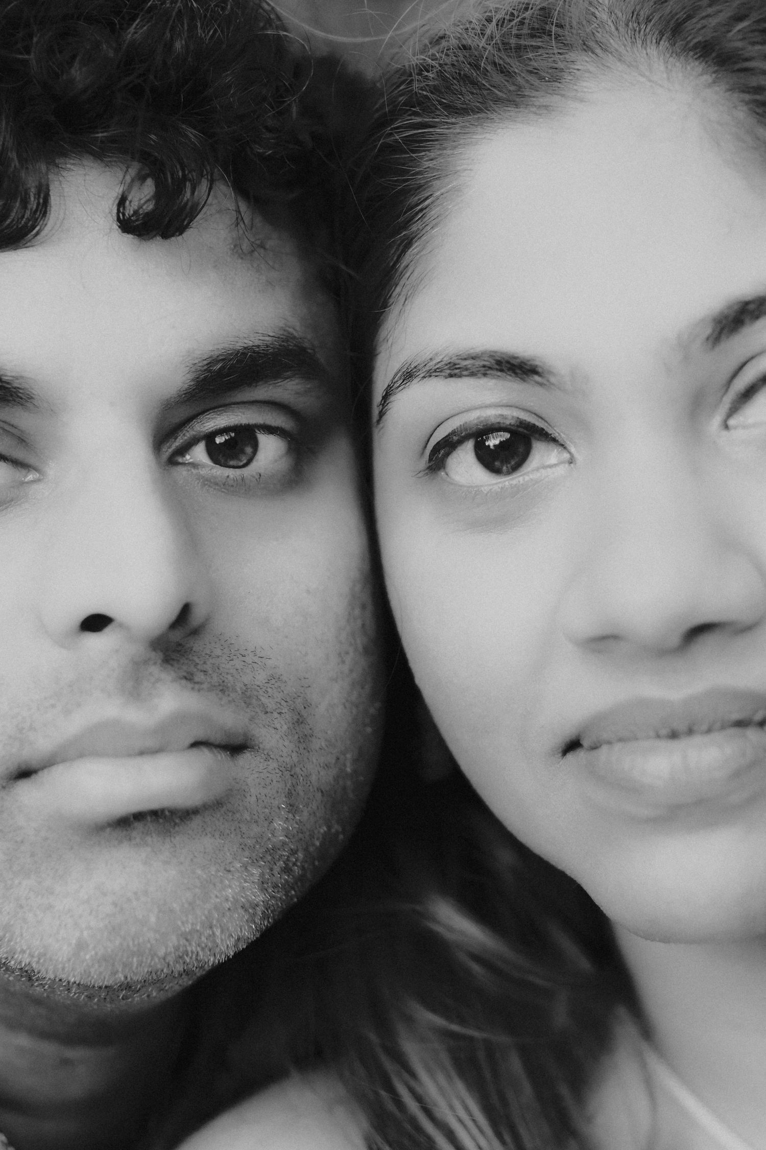 Intimate black and white close-up portrait of a young couple facing the camera.