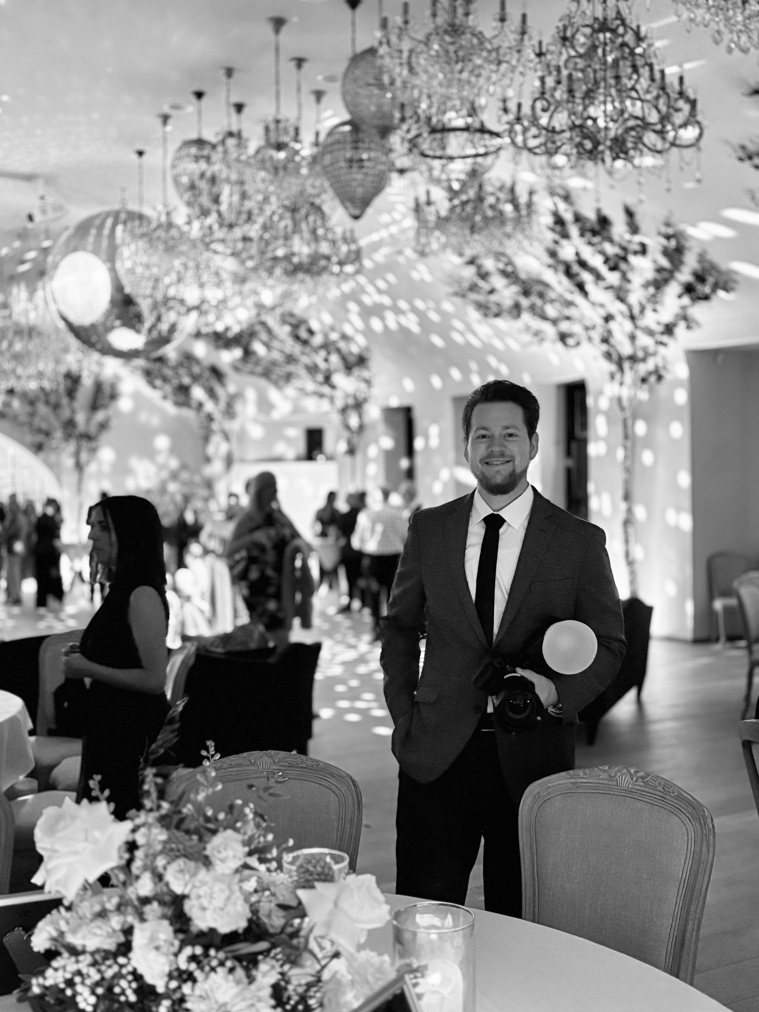 Elegant wedding reception venue decorated with crystal chandeliers and floral arrangements on dining tables.