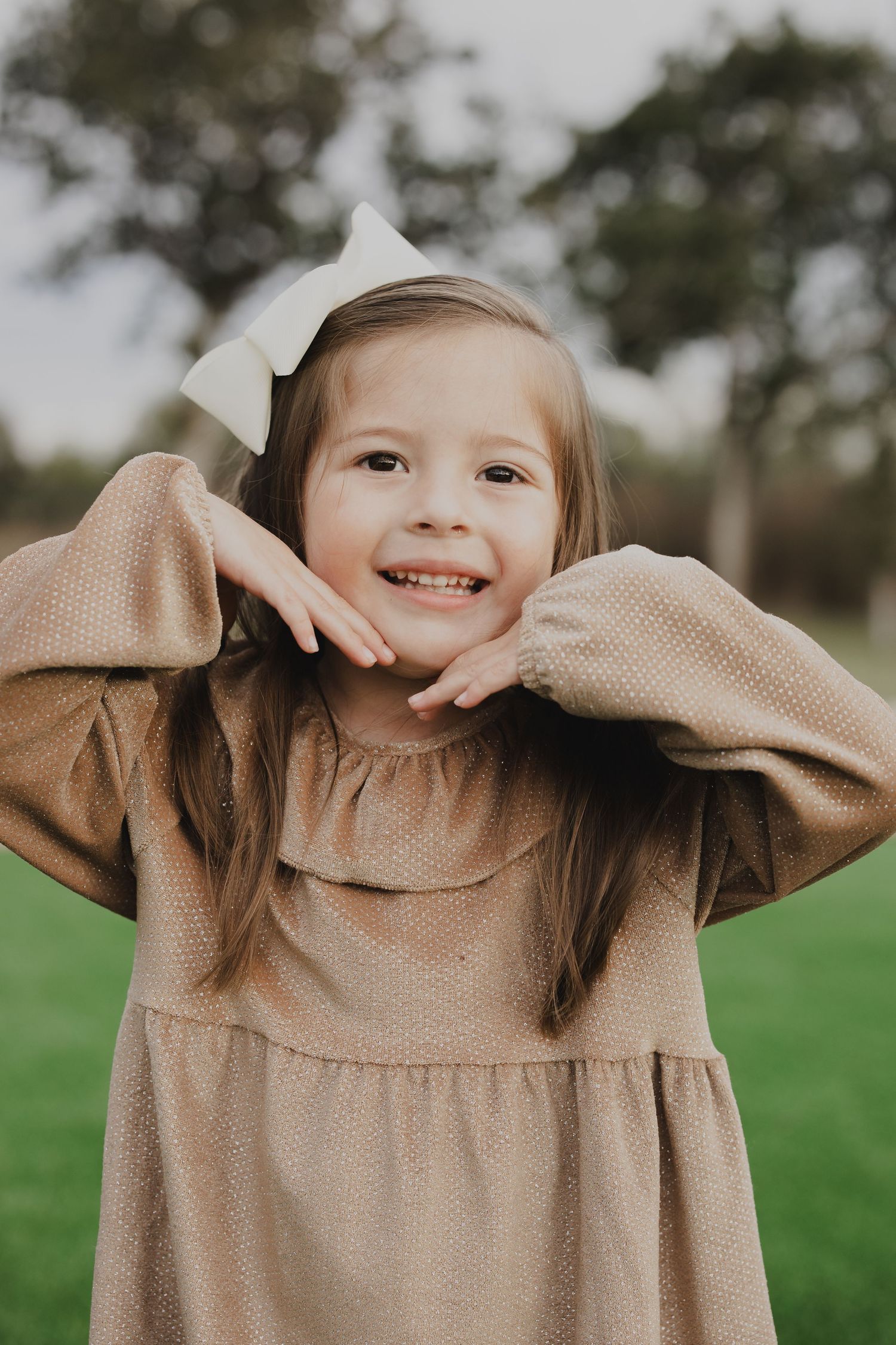 Child playing peek-a-boo with a tan sweater in a playful outdoor photo series.