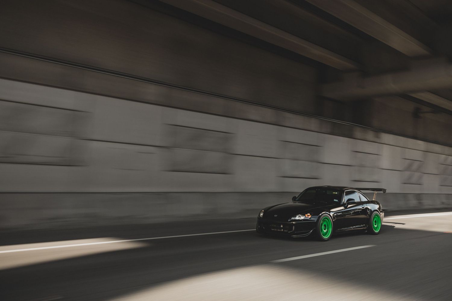 Black sports car racing through an underpass at high speed.