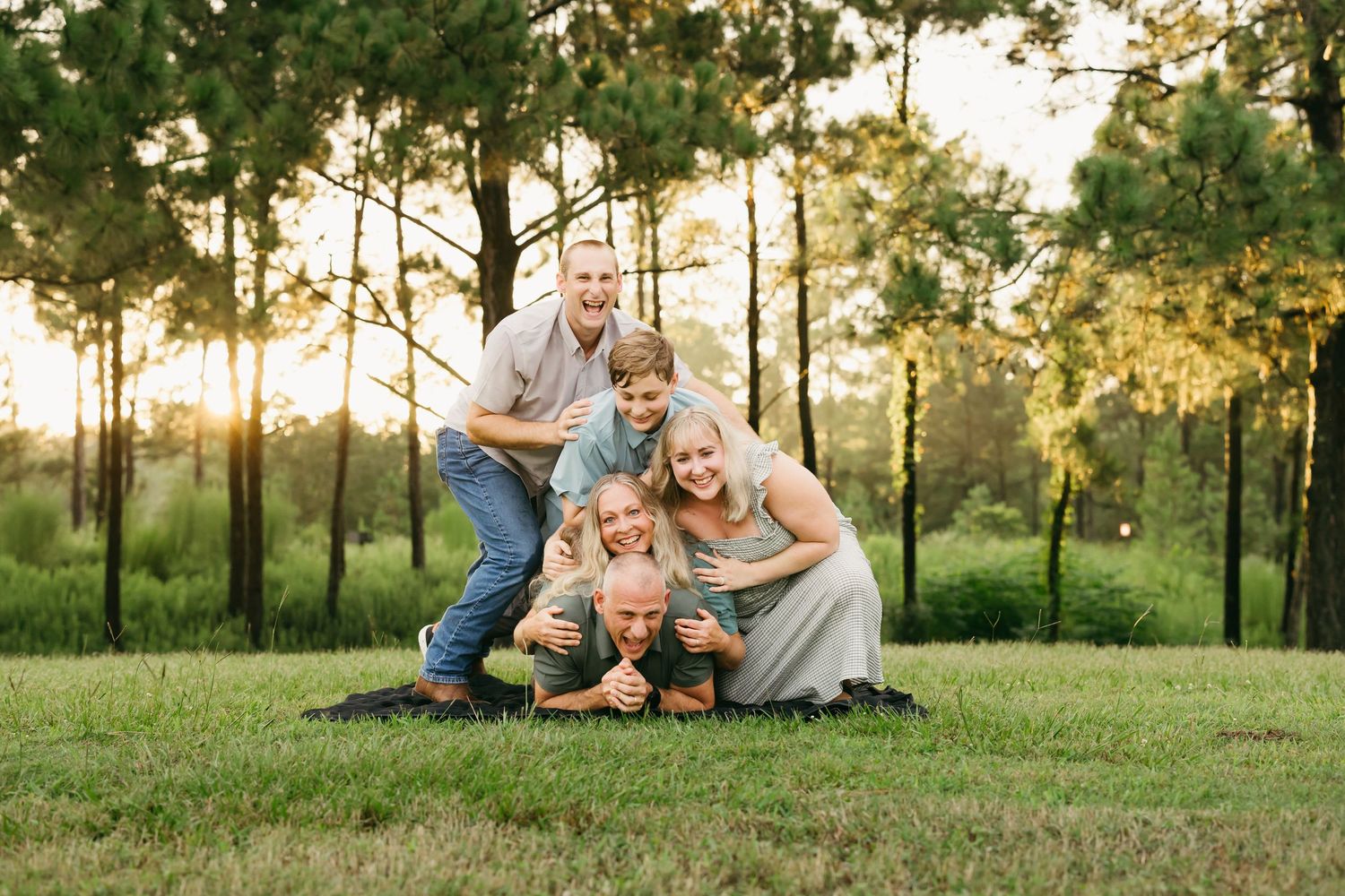 A family shares a playful moment together on grass during golden hour.