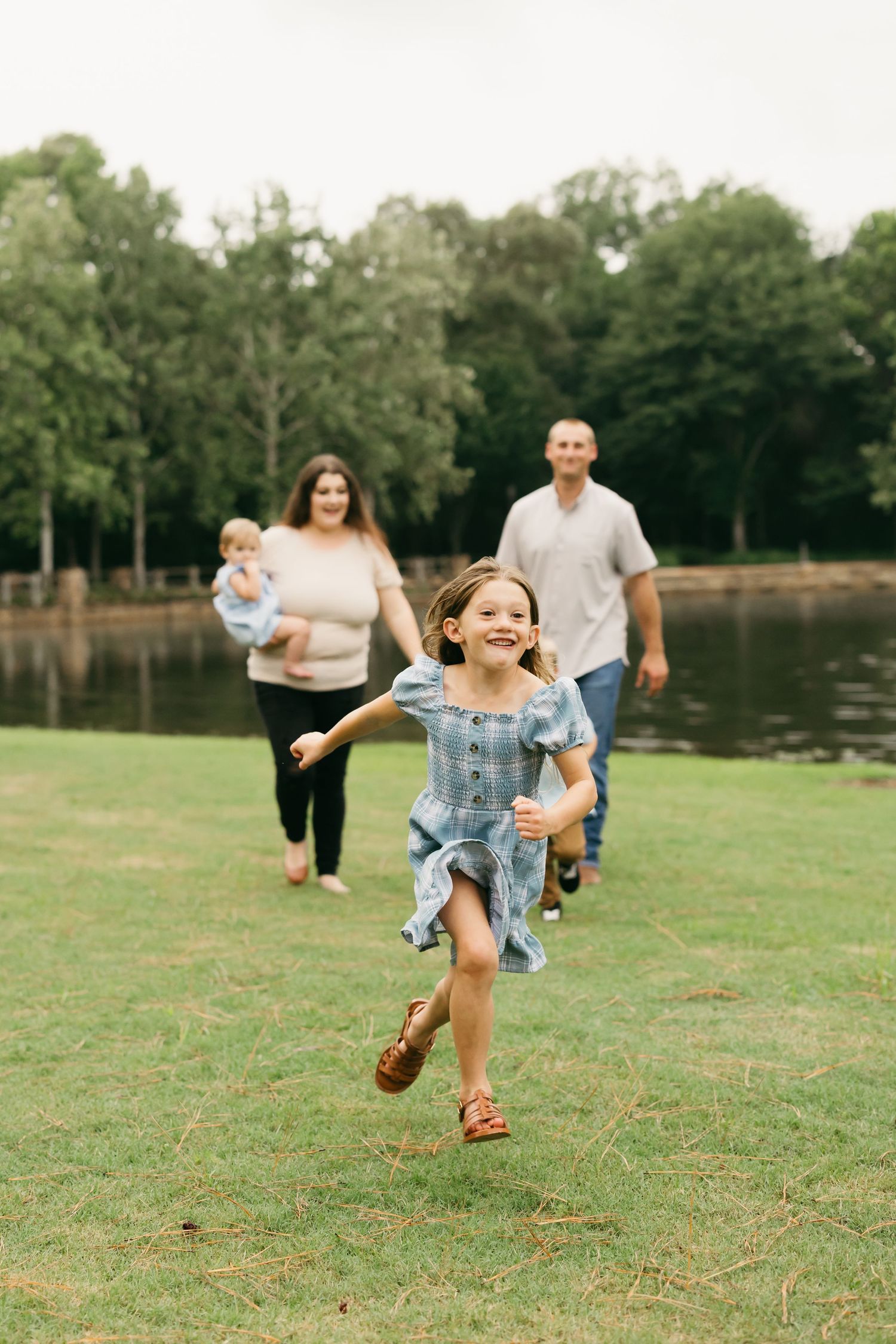 Energetic group playing and running together on grass field near a lake.