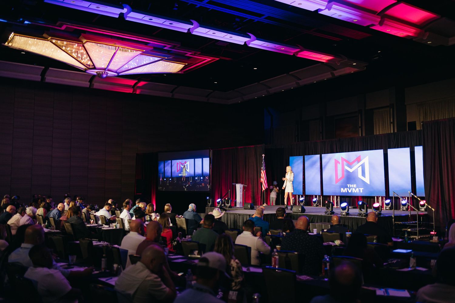 Wide shot of conference room with dramatic purple and red ceiling lighting.