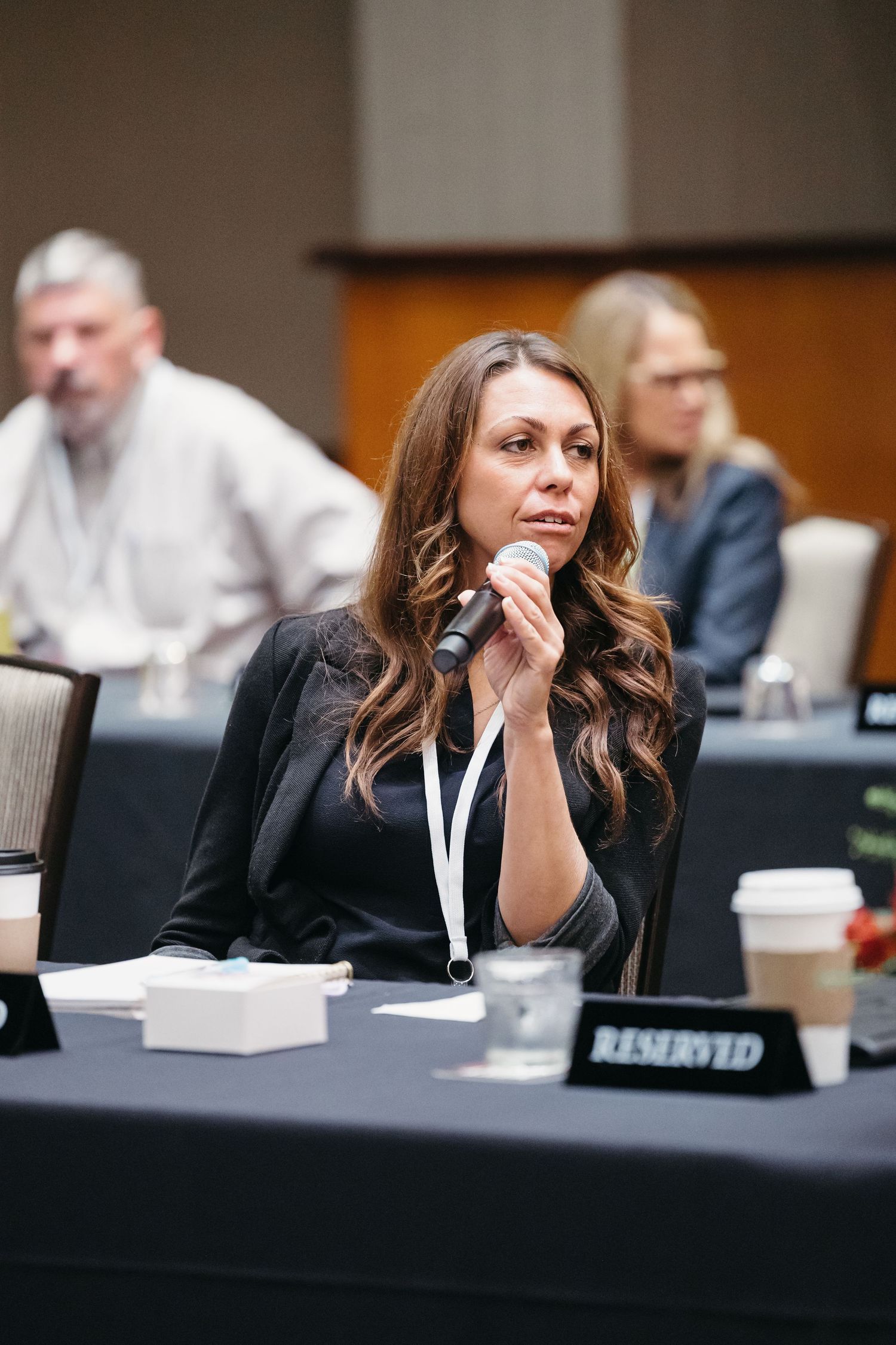 A business professional attending a conference sits thoughtfully at a meeting table.