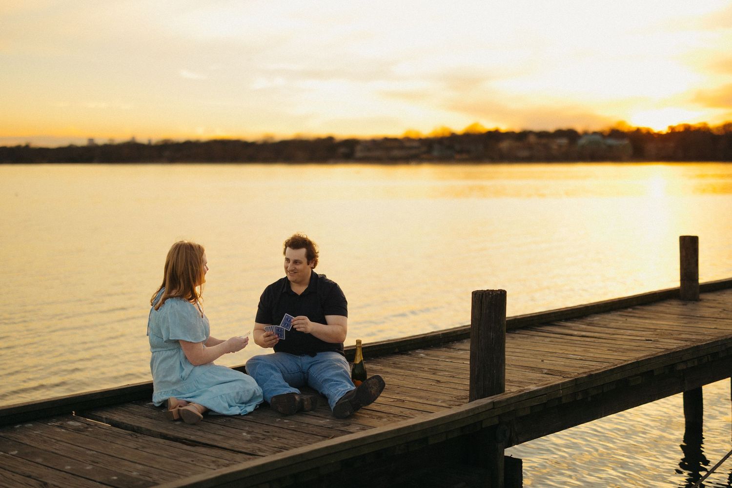 Couple sitting on a wooden dock sharing a romantic sunset moment by the calm lake.