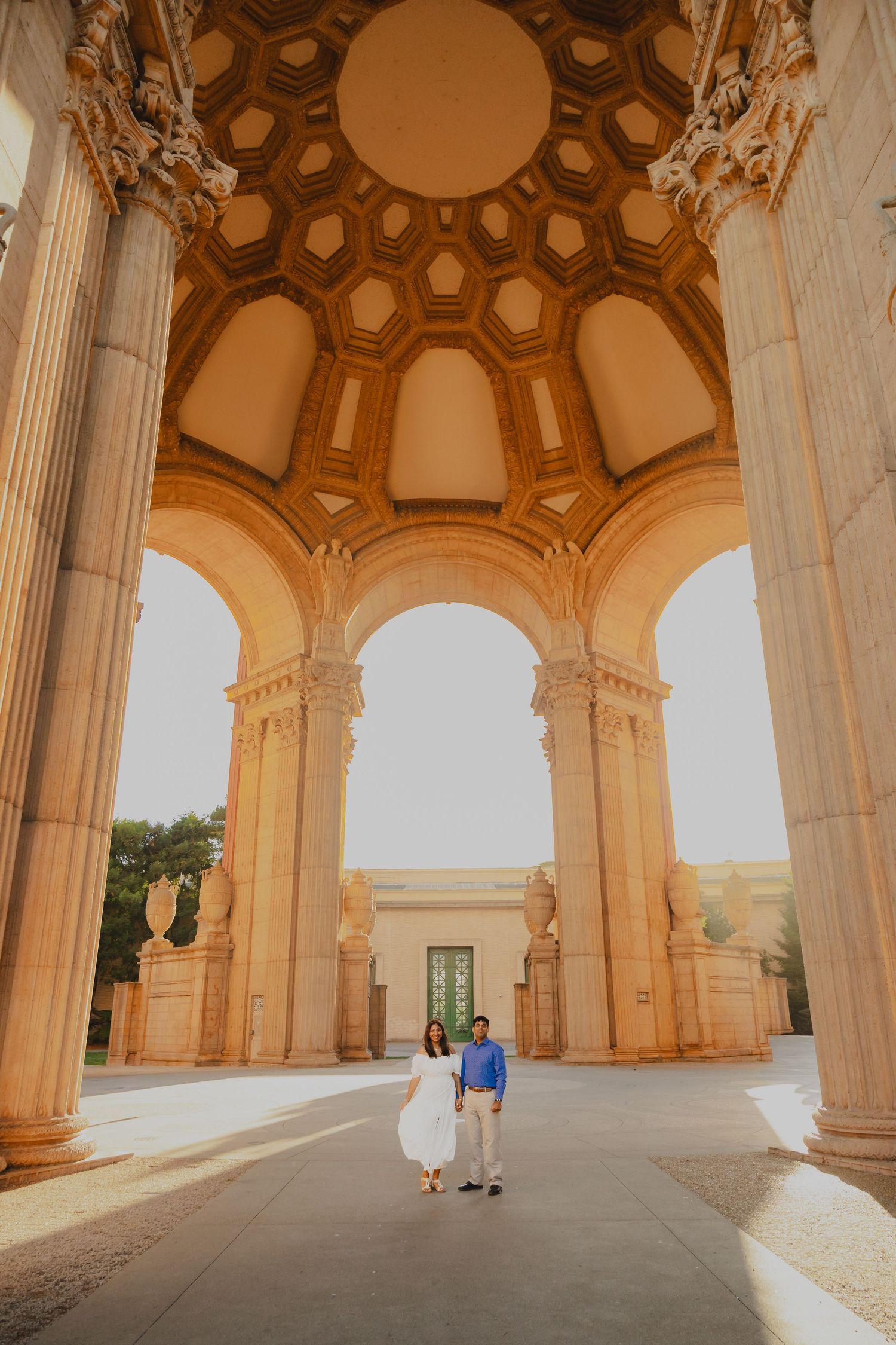 Couple standing under ornate arched rotunda at Palace of Fine Arts in San Francisco.