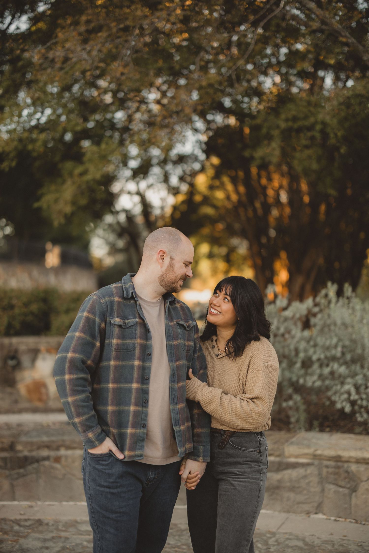 Couple laughing together outdoors during autumn golden hour photoshoot.