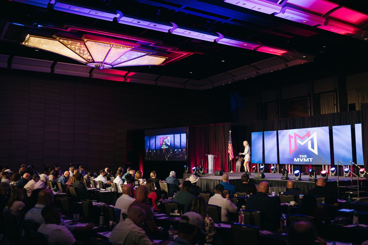 Conference hall setup with colorful lighting and digital displays spanning across ceiling.