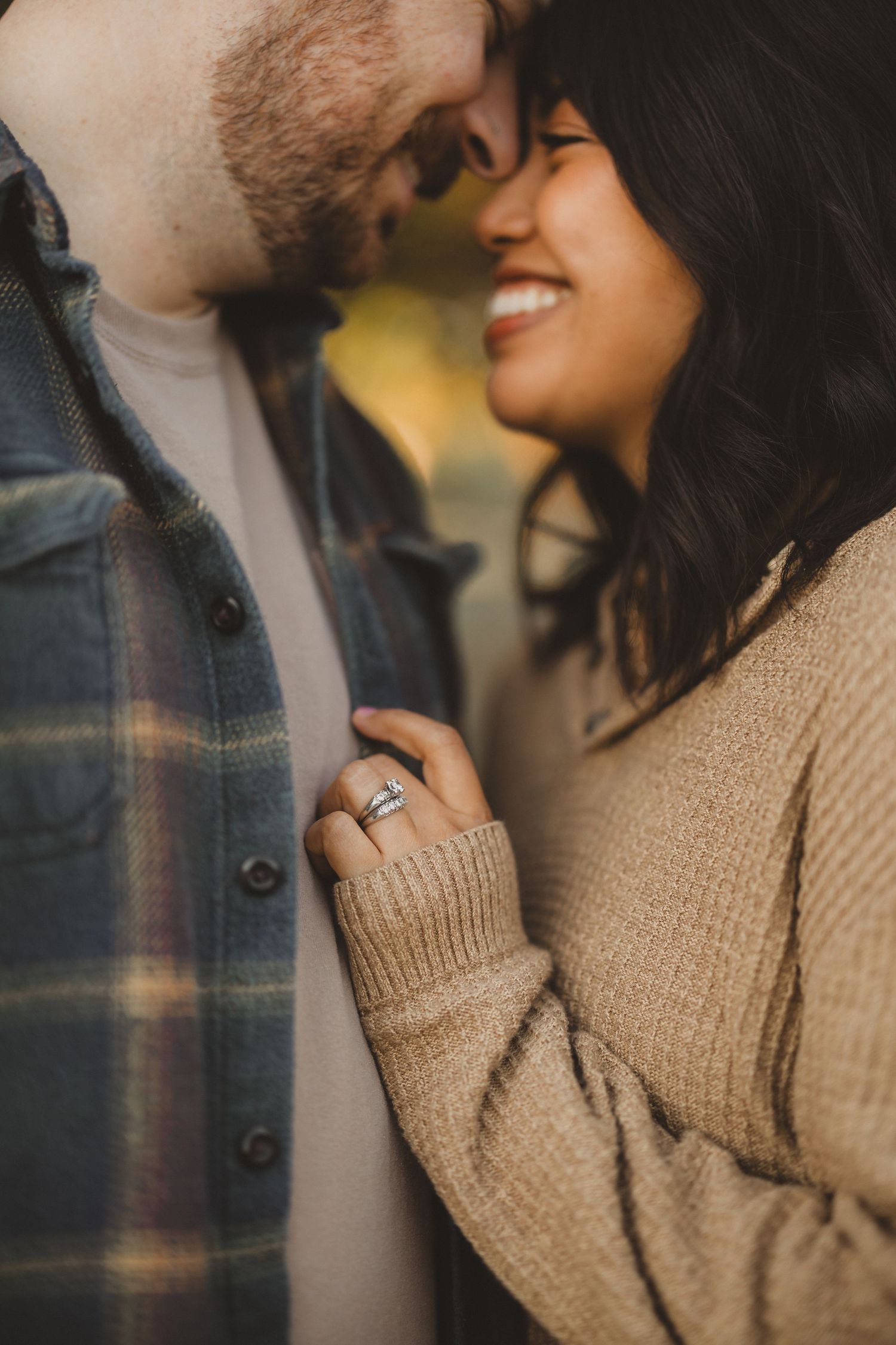 Intimate close-up of couple laughing together while wearing cozy fall sweaters.