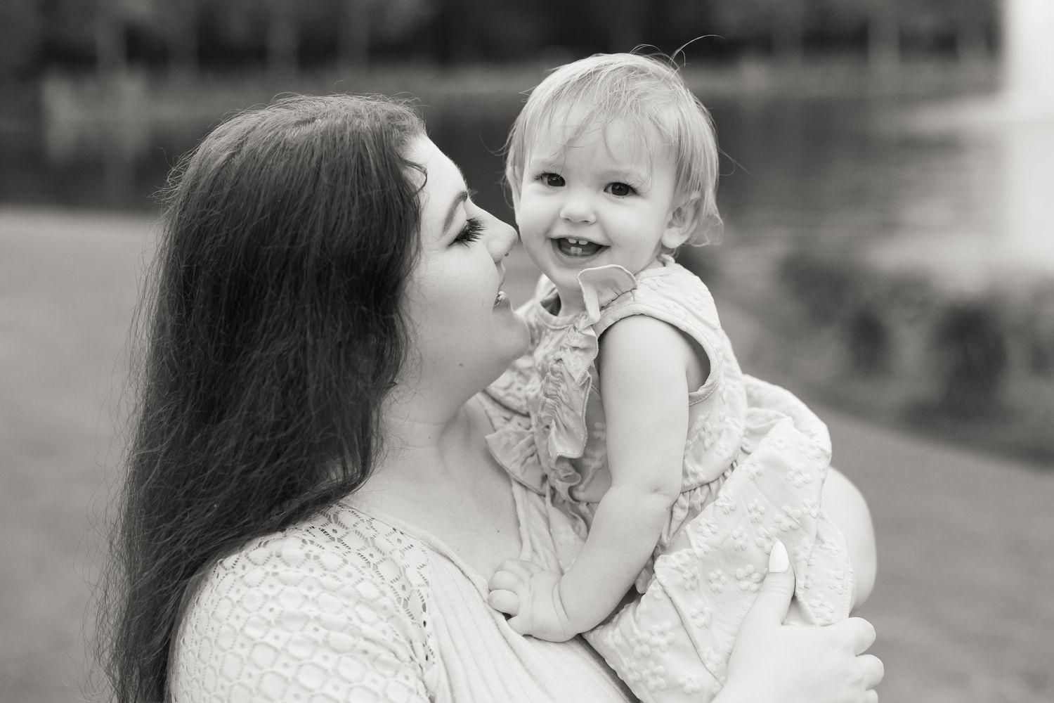 Black and white portrait of tender moment between parent and smiling baby.