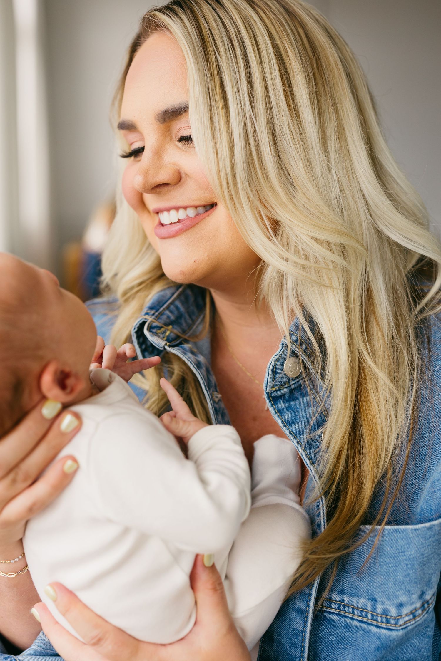 A tender moment captured in a series of photos showing a parent in denim jacket cuddling with a baby in white.