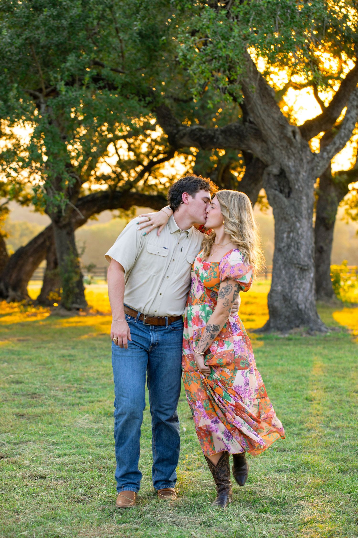 A couple shares a romantic moment in a sun-dappled grove of trees during golden hour.