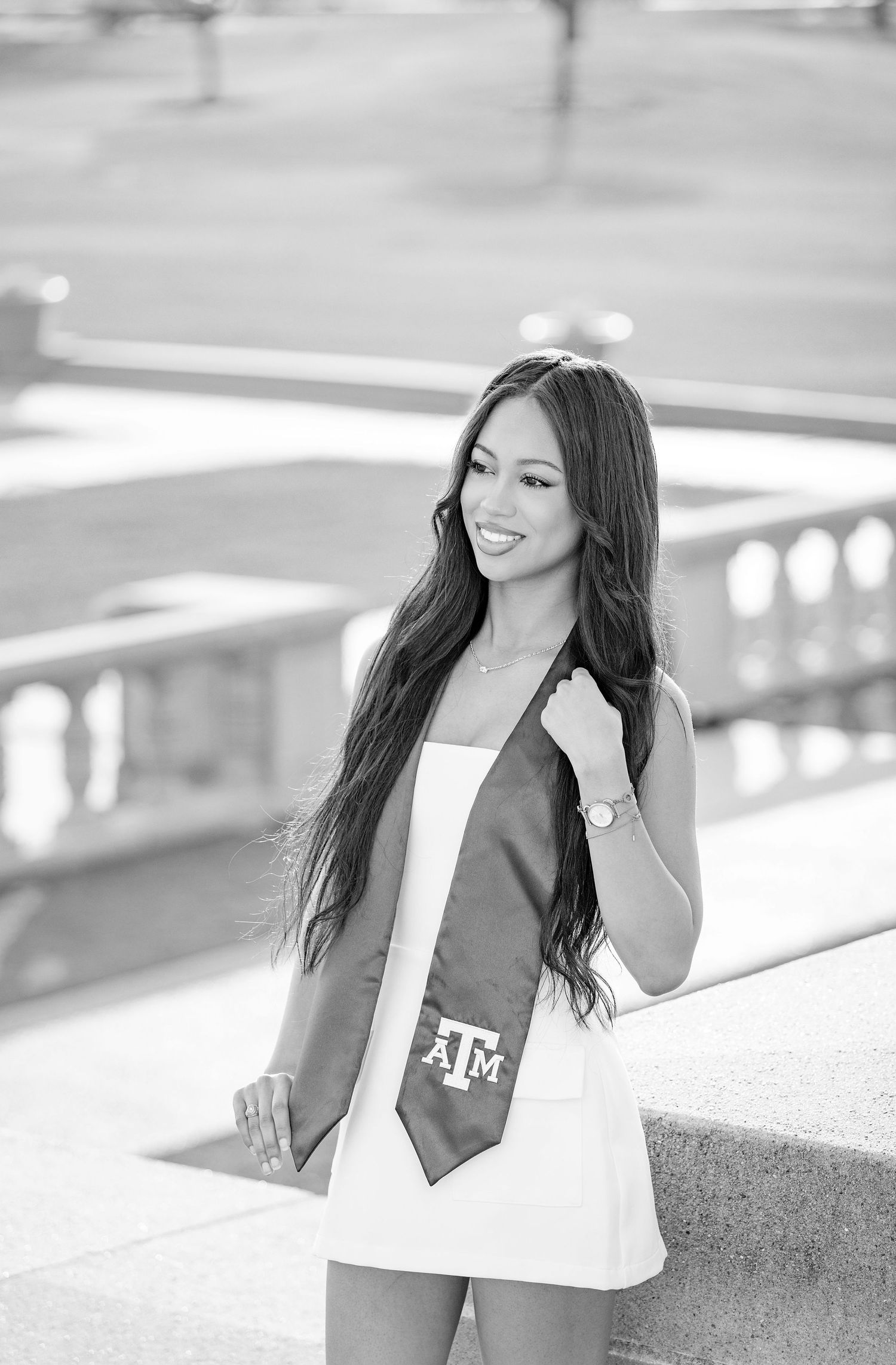 Black and white graduation photos showing a graduate in business attire smiling and posing outdoors on campus.