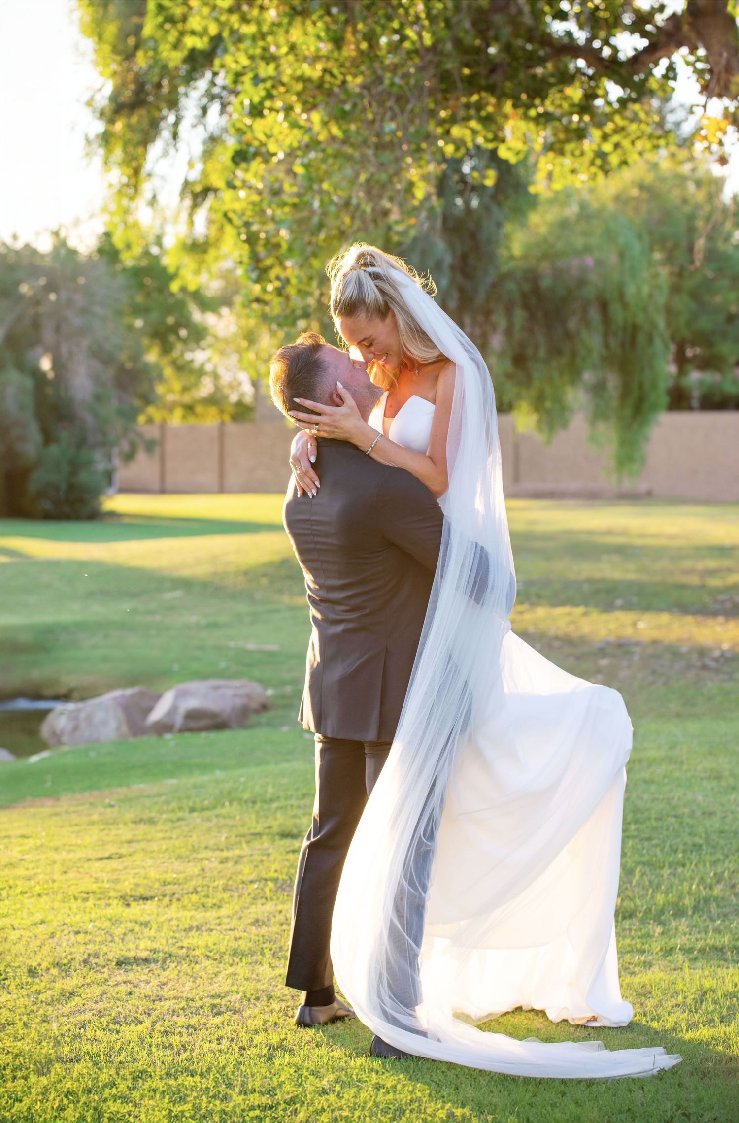 Romantic, whimsical wedding pose with flowing veil against sunset garden backdrop in Scottsdale, Arizona.