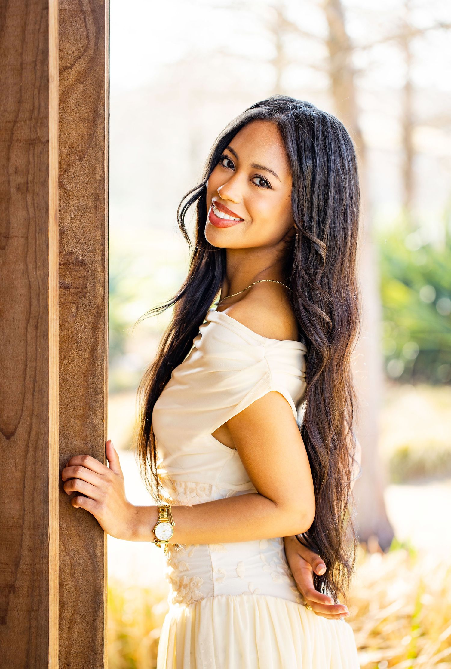 Natural light portraits between wooden pillars showcase flowing white dress and joyful expressions.