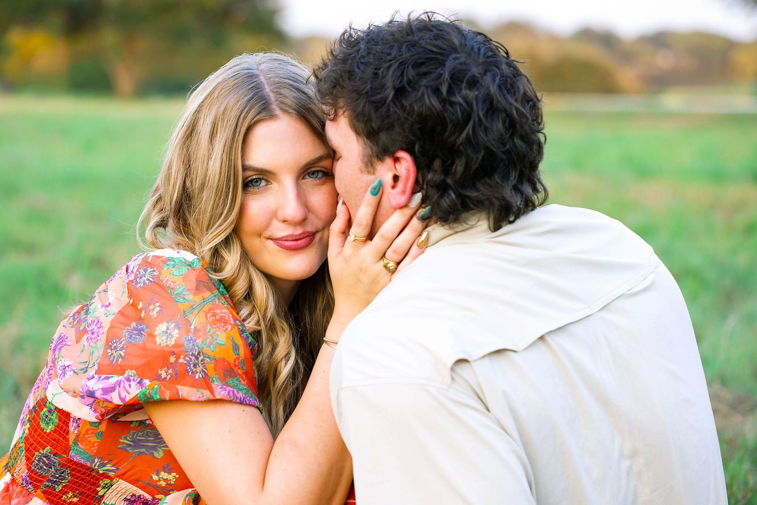 A couple shares tender moments in an outdoor setting wearing white and floral outfits during a romantic photoshoot.
