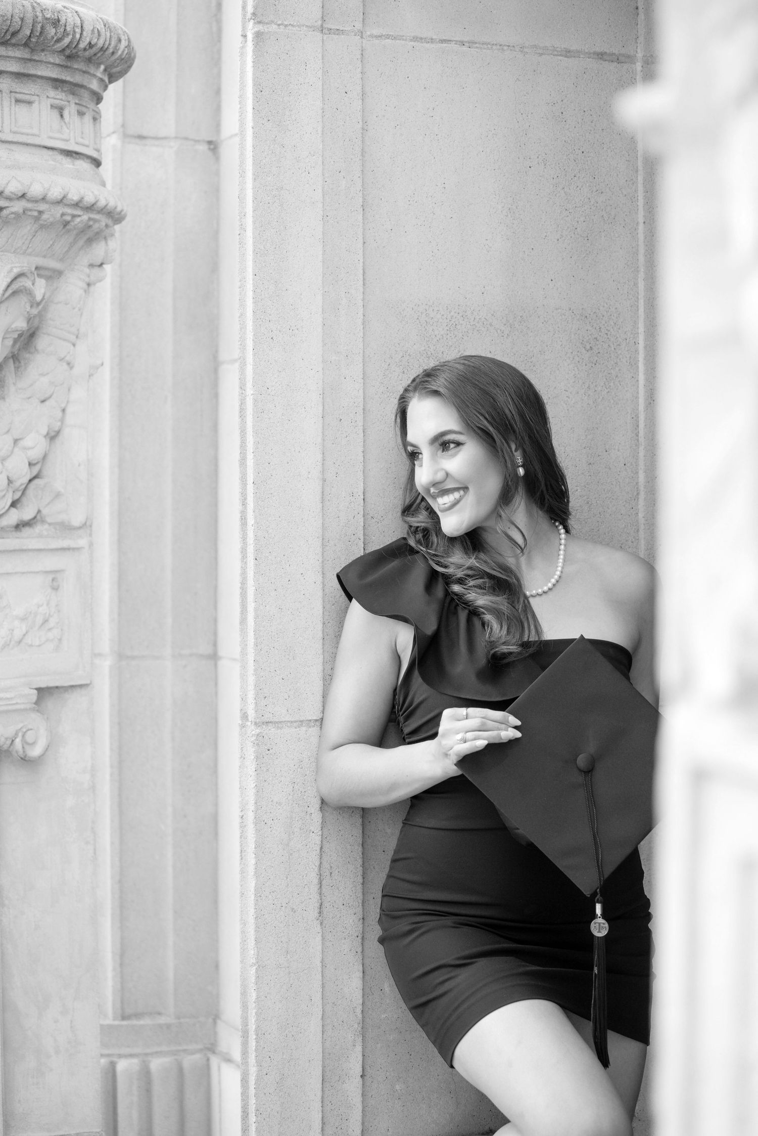 Texas A&M University graduate black formal dress photographed in dramatic black and white against classic stone architecture.