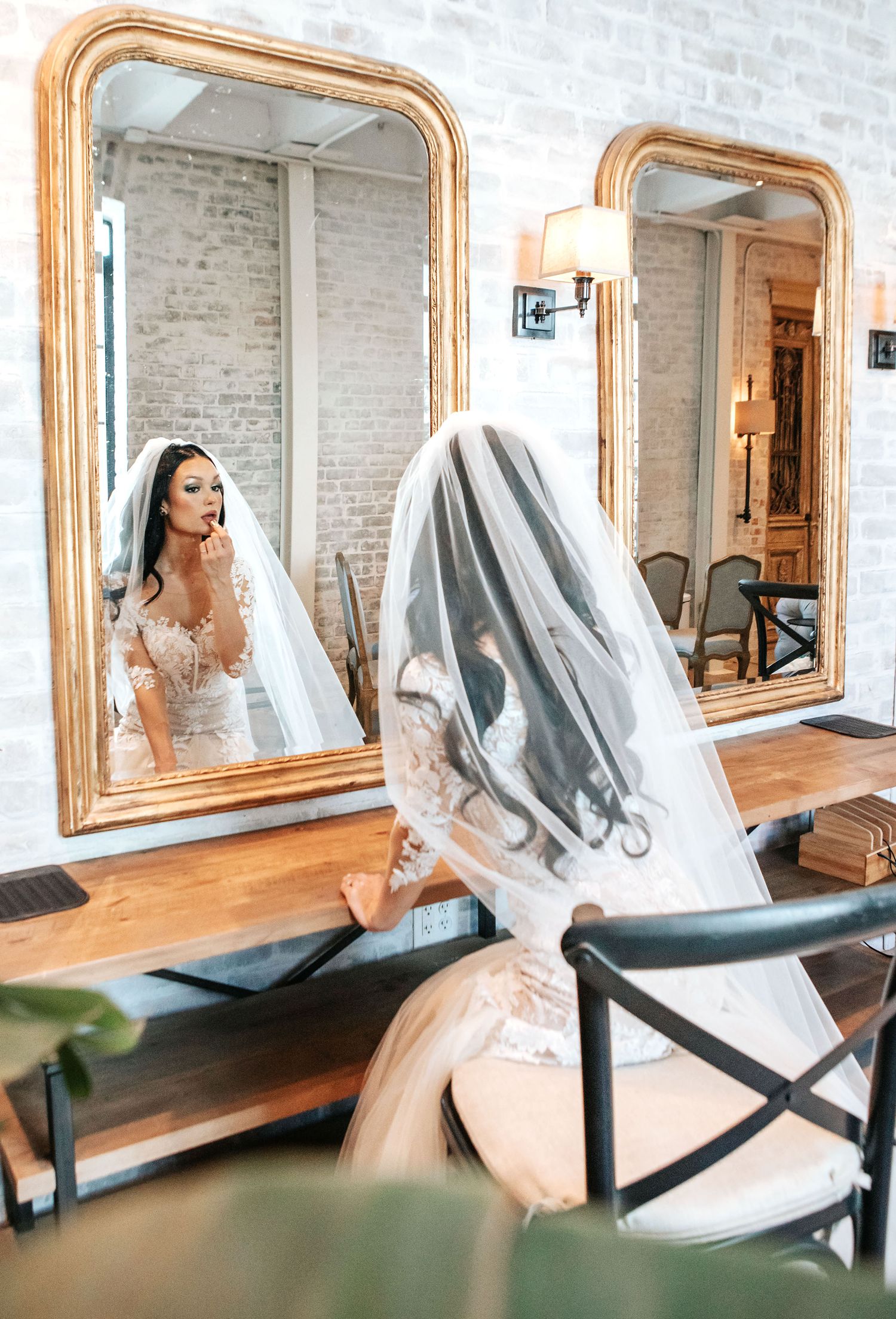 Interior view of a rustic salon with multiple gold-framed mirrors and styling chairs along a white brick wall.