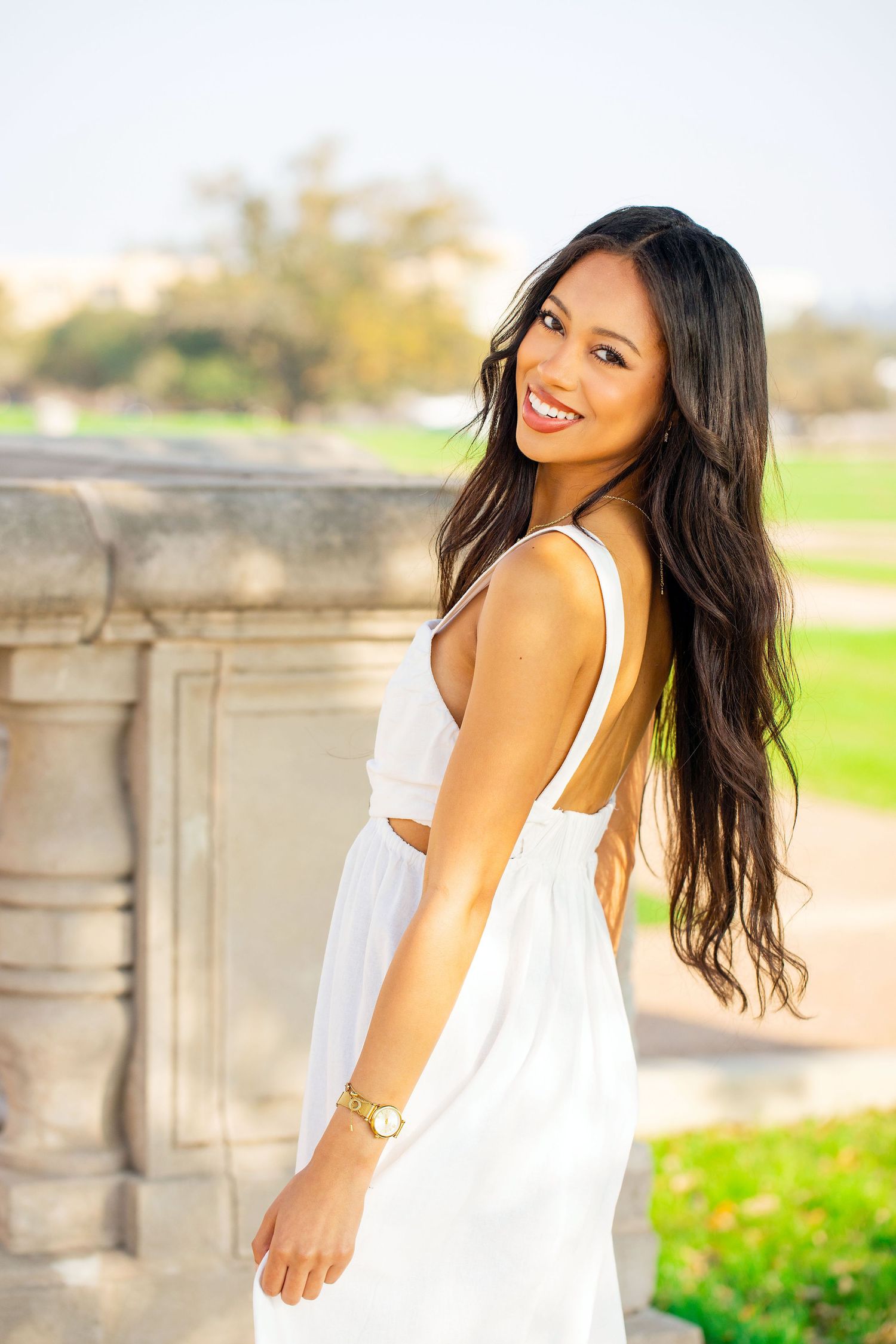 Joyful portrait session in a white sundress against a bright outdoor background.