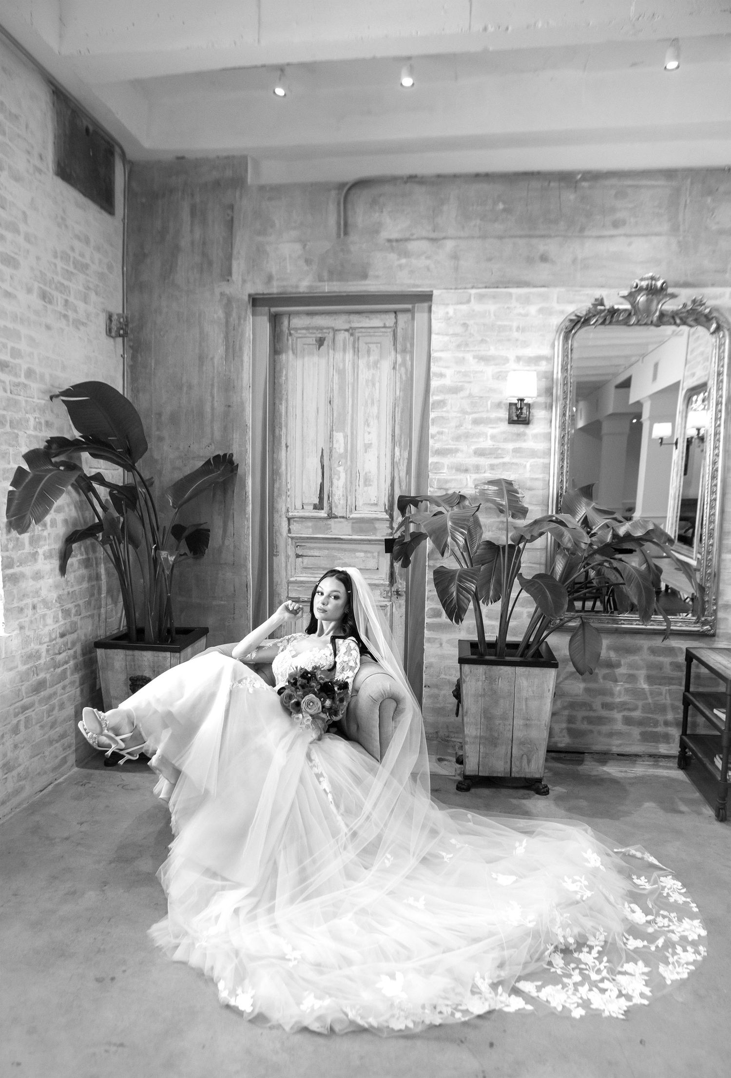A series of black and white wedding photos showing a flowing white dress in an industrial brick-walled space.
