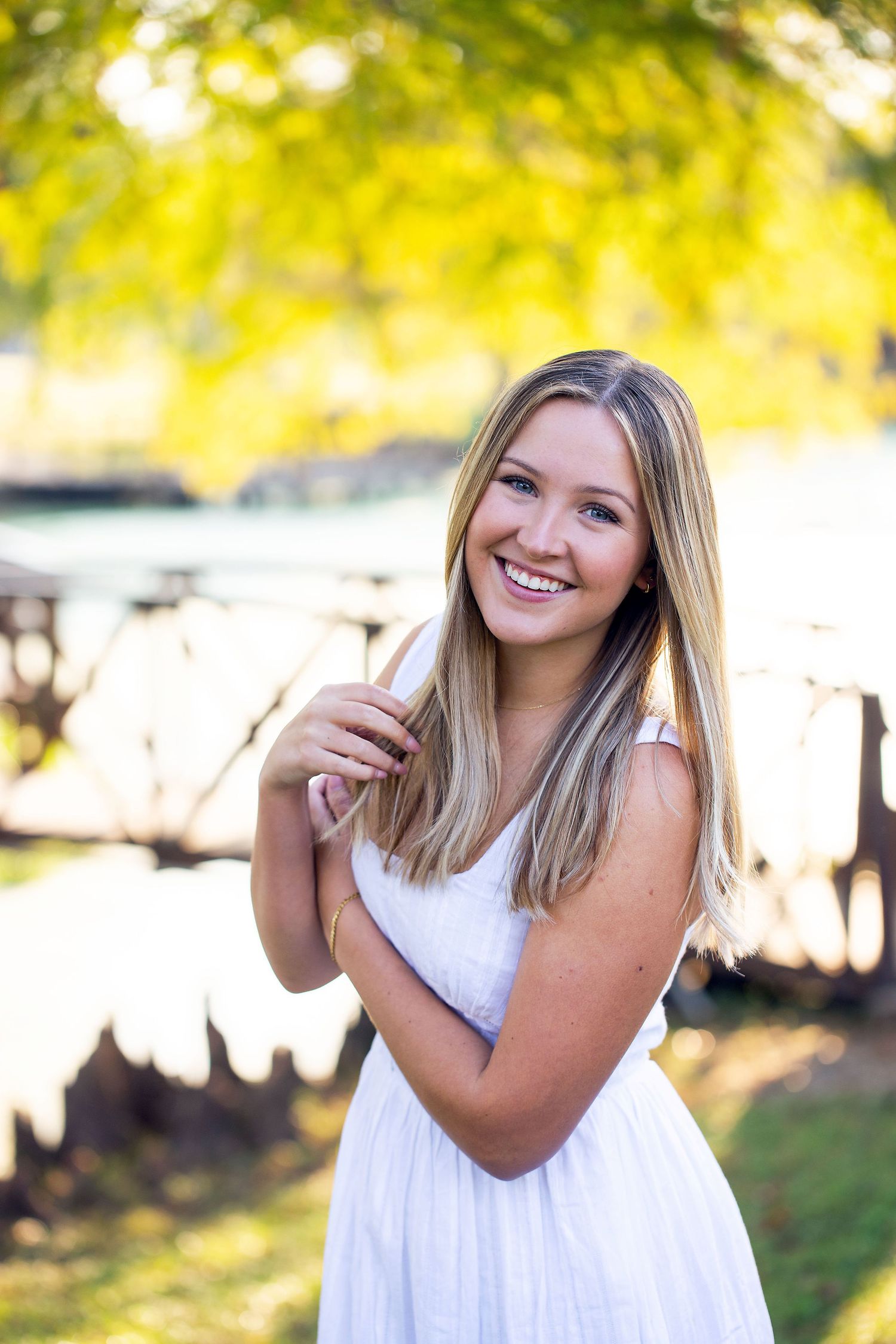 Texas A&M University graduate outdoor portrait session in natural sunlight with white sundress at Gabbard Park.