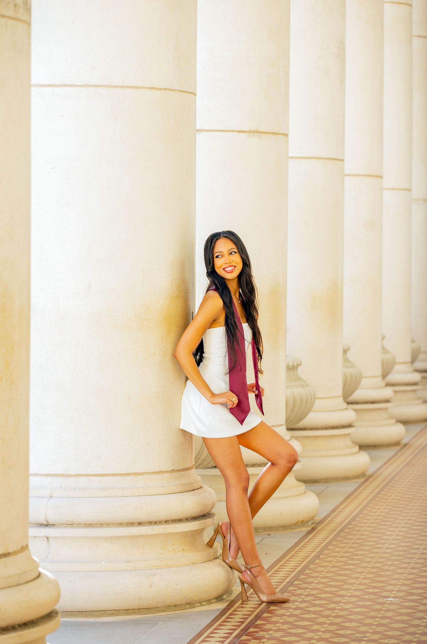 Playful graduation portraits taken in architectural setting with white columns.
