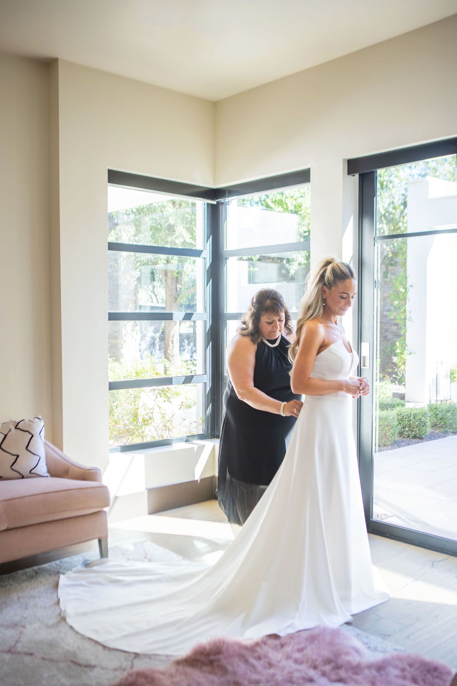 A wedding dress fitting moment in a bright corner room with large windows and a flowing white gown in Scottsadale, Arizona.