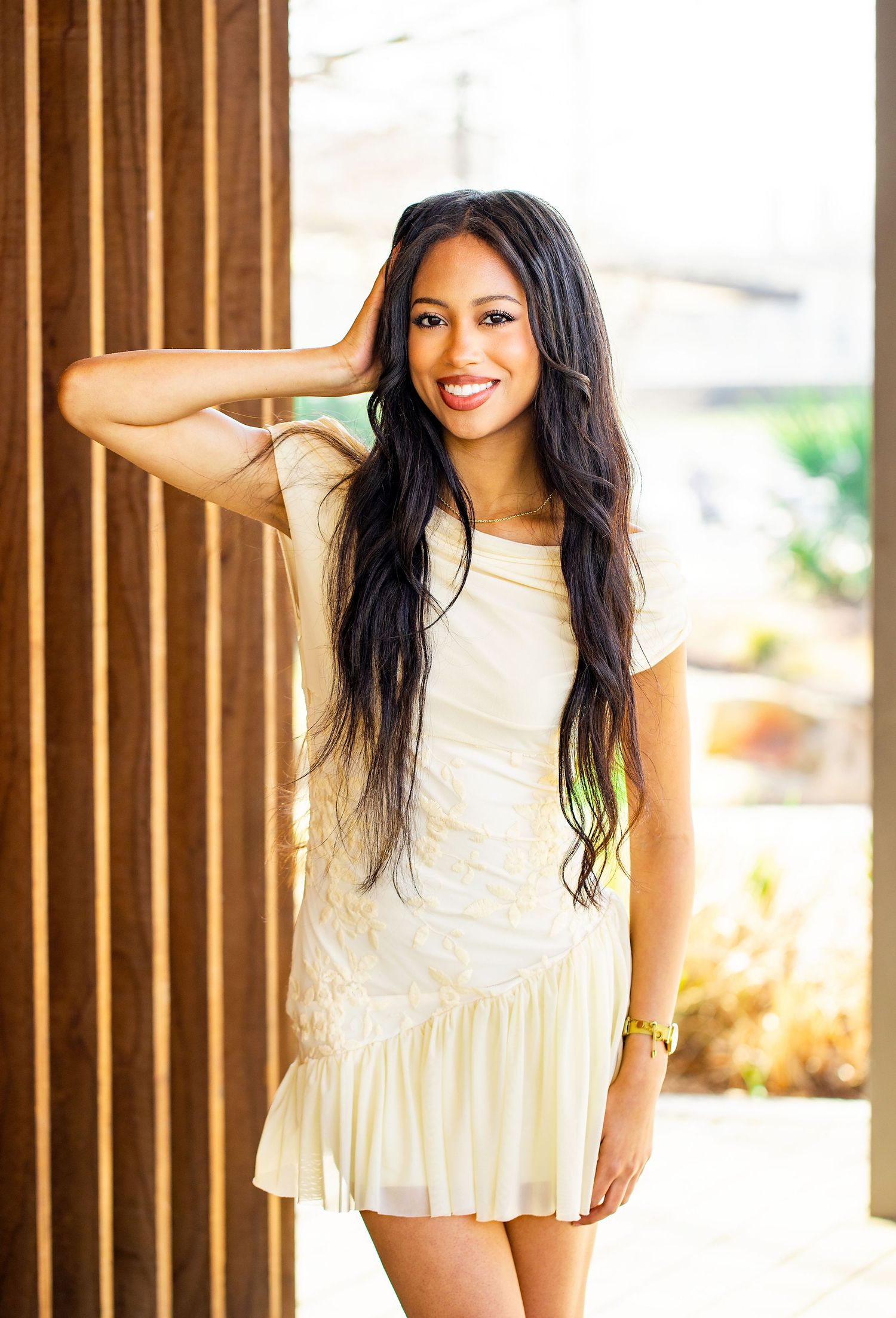 Playful portraits against wooden slat wall feature white ruffled dress.