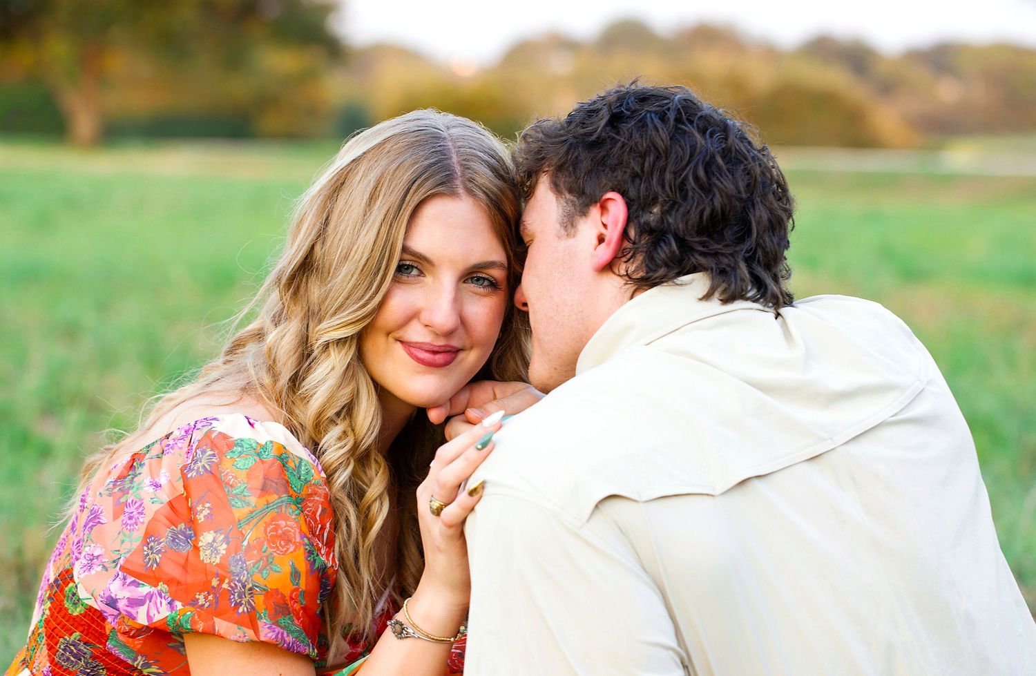 A tender moment between a couple in floral dress and white shirt against a natural backdrop In Brenham Texas.